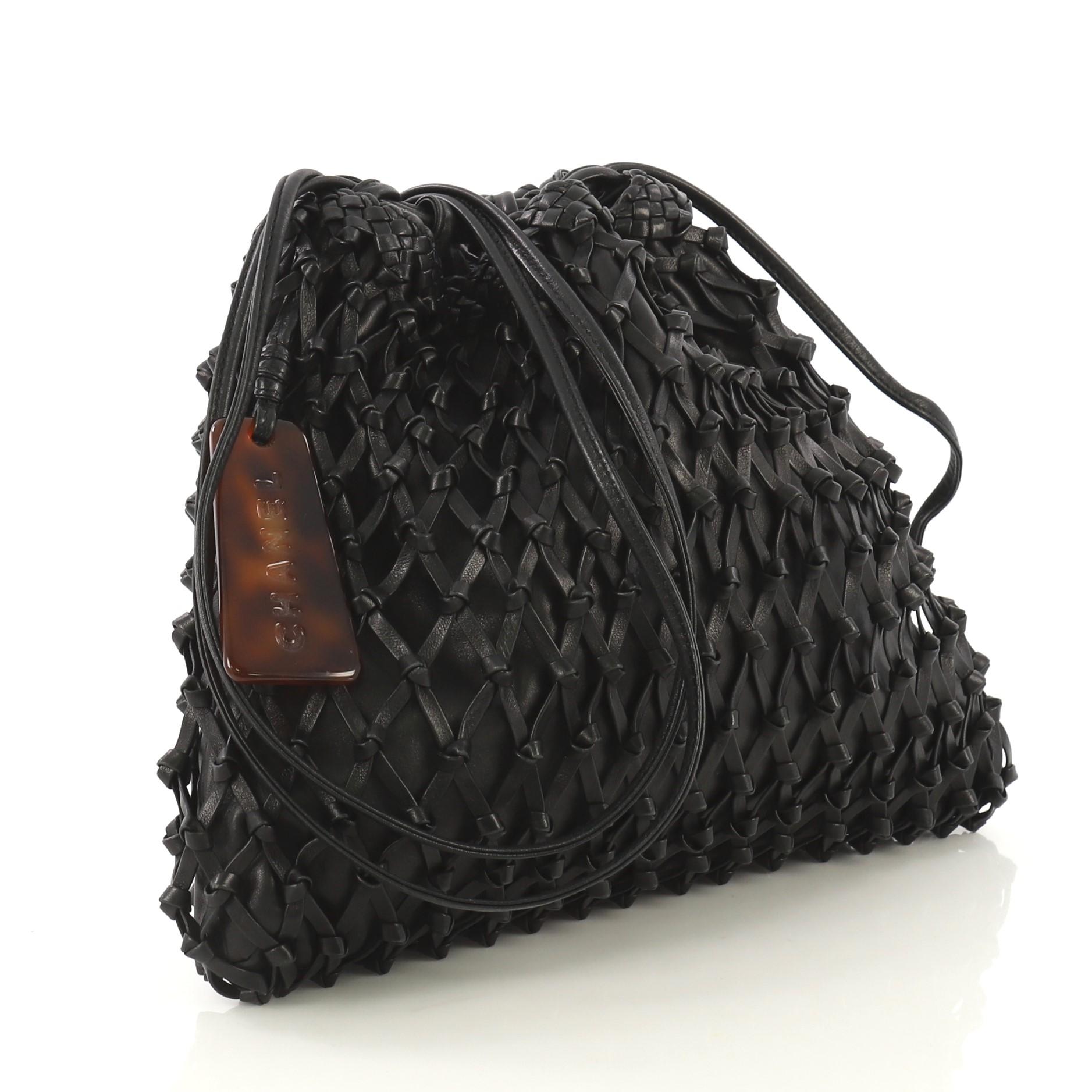 This Chanel Vintage Resin Bucket Bag Woven Leather Medium, crafted from black woven leather, features leather shoulder strap and gold-tone hardware. It opens to a black leather interior with zip pocket. Hologram sticker reads: 5210957. 

Condition: