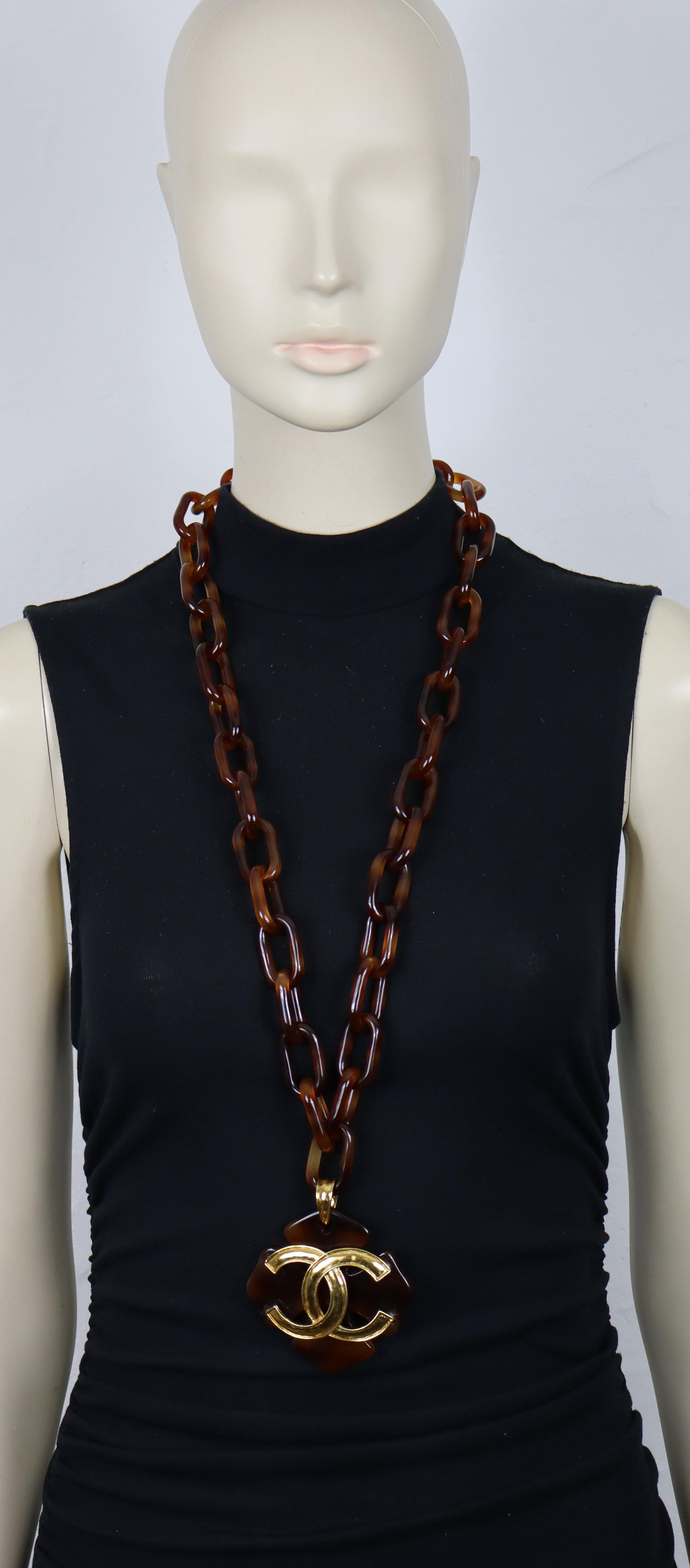 Collana a catena in resina marrone vintage di Chanel con un grande logo CC in tonalità oro al centro di un ciondolo a forma di quadrifoglio.

Dalla collezione primavera 1994 di Chanel.

Can indossa la catena lunga singola, raddoppiata o come