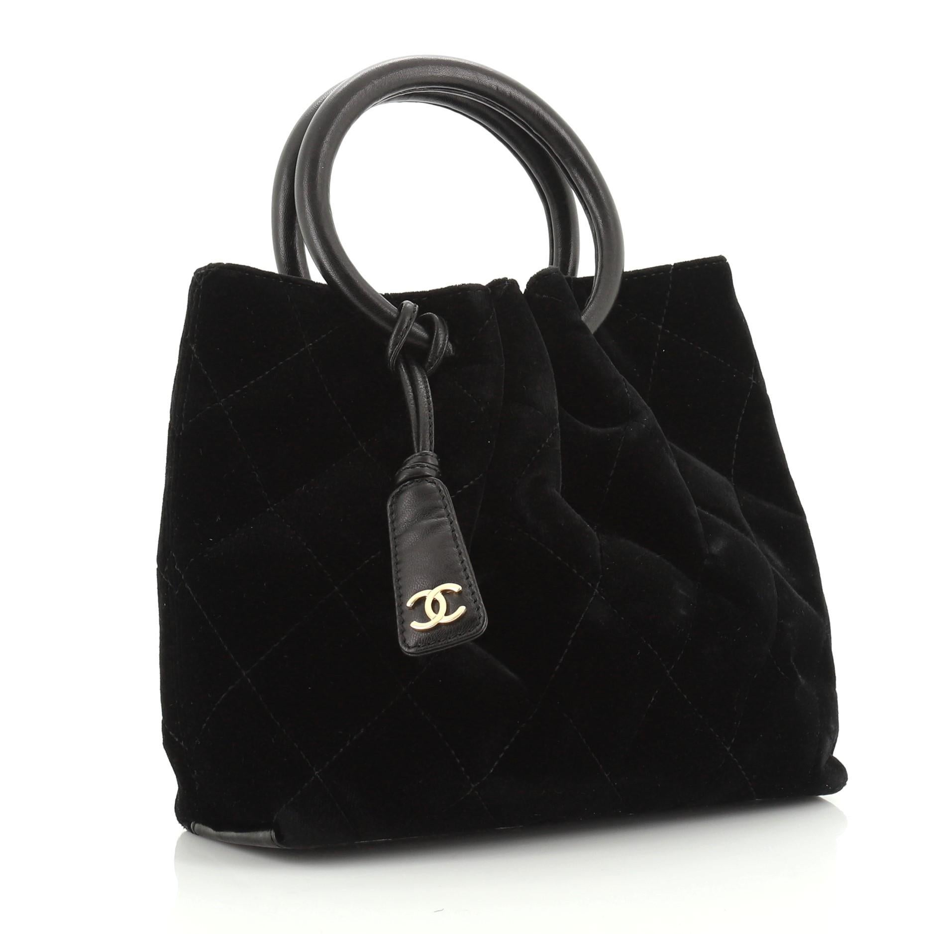 This Chanel Vintage Ring Handle Bag Quilted Velvet Small, crafted from black quilted velvet, features dual ring handles, pleated detailing and gold-tone hardware. It opens to a black fabric interior. Hologram sticker reads: 6878580. 

Condition: