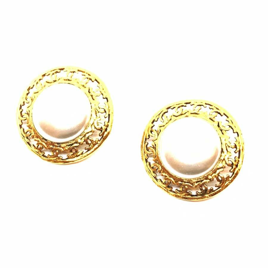 The pair of earrings is a vintage model from Maison CHANEL. Round in shape, they each have in their center a pearly ball encircled by a frieze of CC in metal gilded with fine gold. All the vintage spirit of CHANEL in this pair of clips to keep as a