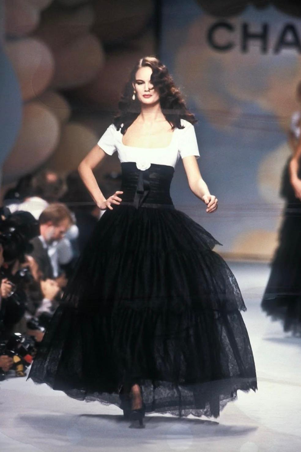 This stunning vintage Chanel gown from the Spring/Summer  1988 collection is a timeless masterpiece that exudes elegance and sophistication. The dress features a striking contrast between the crisp white cotton bodice and the flowing black lace