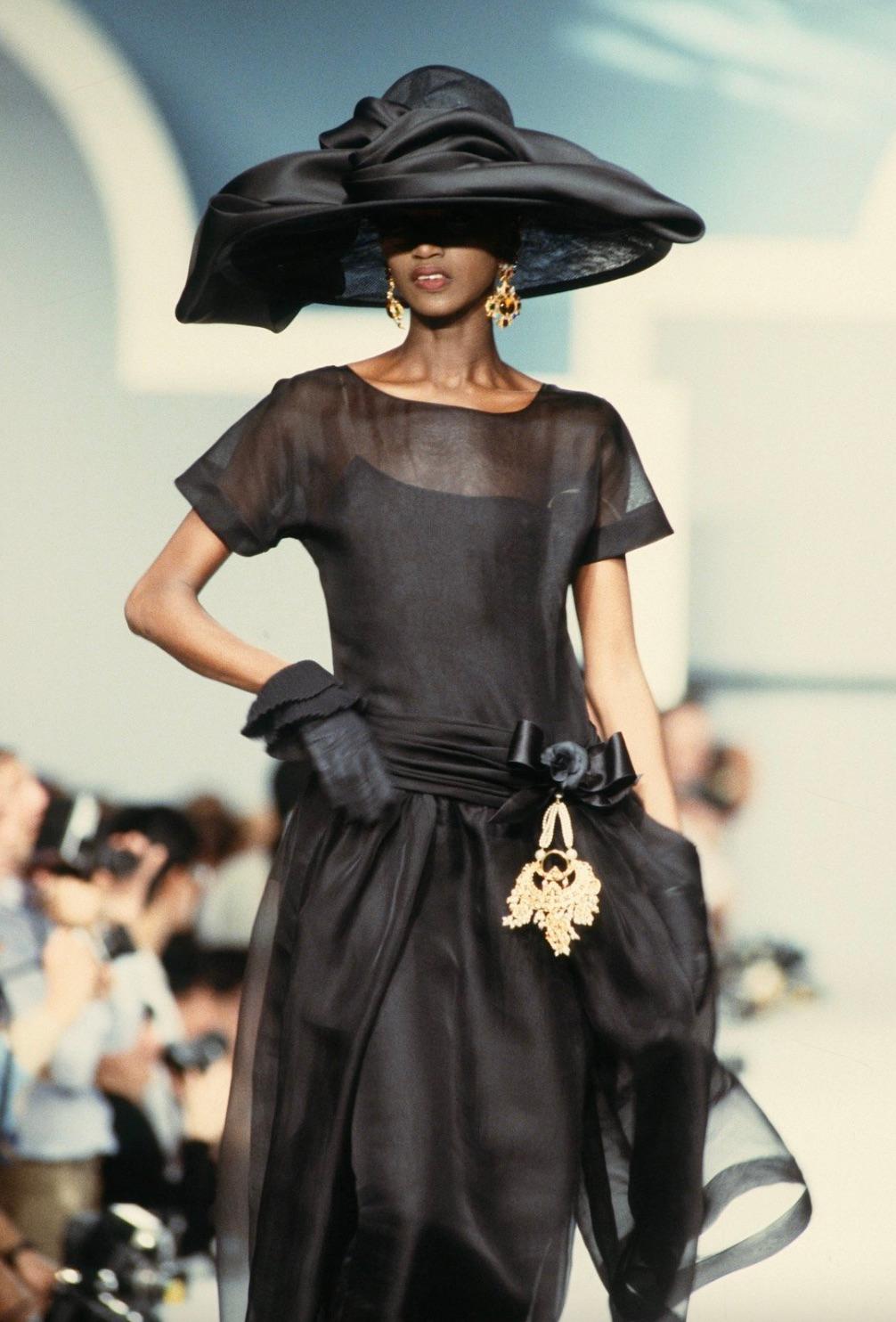 Step back in time with the chic Chanel vintage Spring/Summer 1989 black gown. Crafted from luxurious black silk, this exquisite piece features a sheath silhouette with delicate detailing. Adorned with three silk bows along the back, fastened with