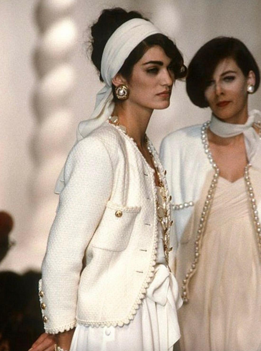 Diese ikonische Chanel-Jacke aus der Frühjahrskollektion 1990 ist ein herausragendes Stück Modegeschichte. Sie ist aus ecrufarbenem Tweed gefertigt und verfügt über die für das Haus charakteristischen 24-karätigen vergoldeten Knöpfe mit dem