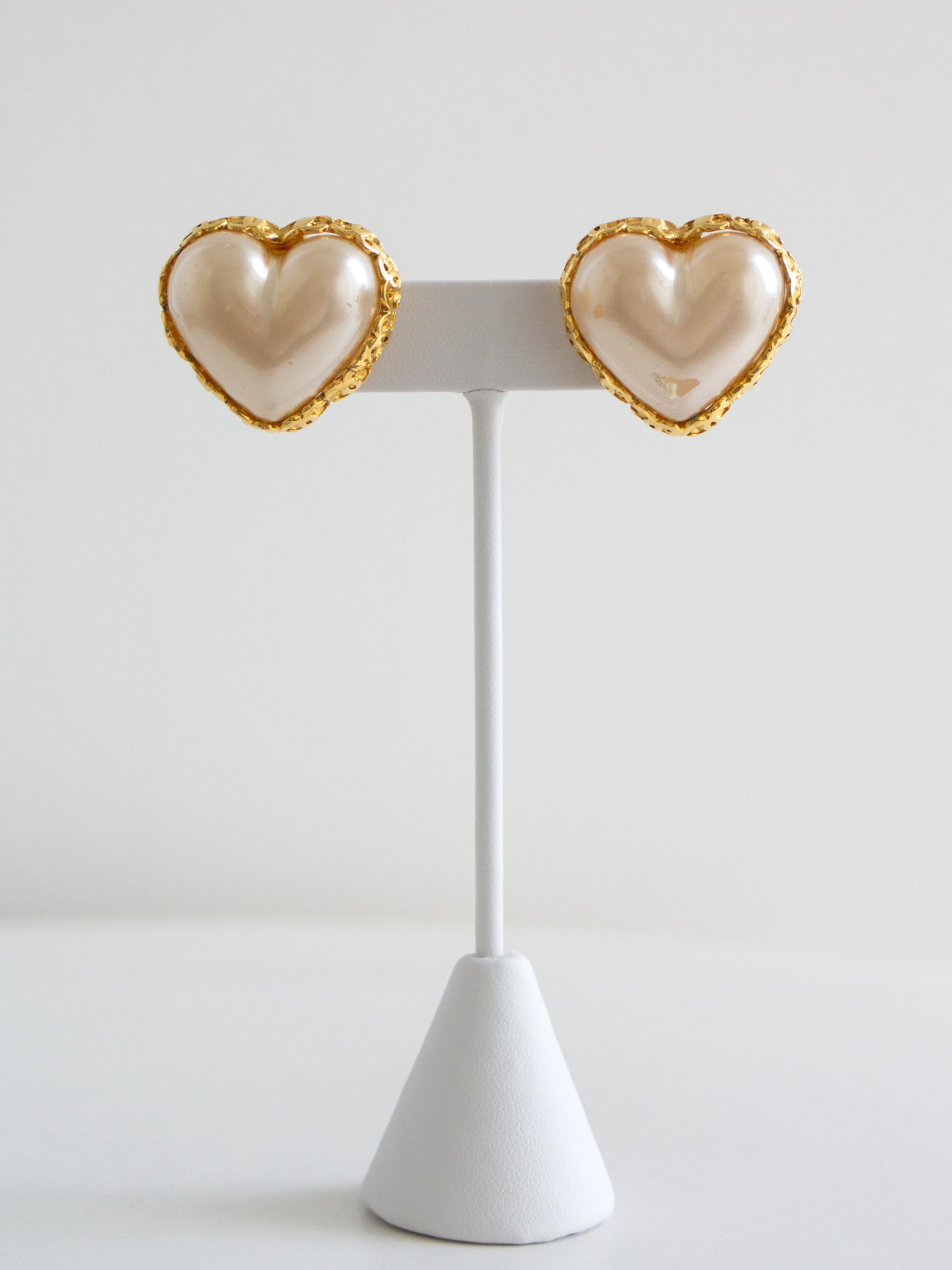 From Chanel’s Spring 1992 collection (collection 28), these heart-shaped clip-on earrings capture the romantic and playful spirit of early-'90s Chanel. The design features oversized puffed hearts in luminous ivory-toned faux pearl, bordered by