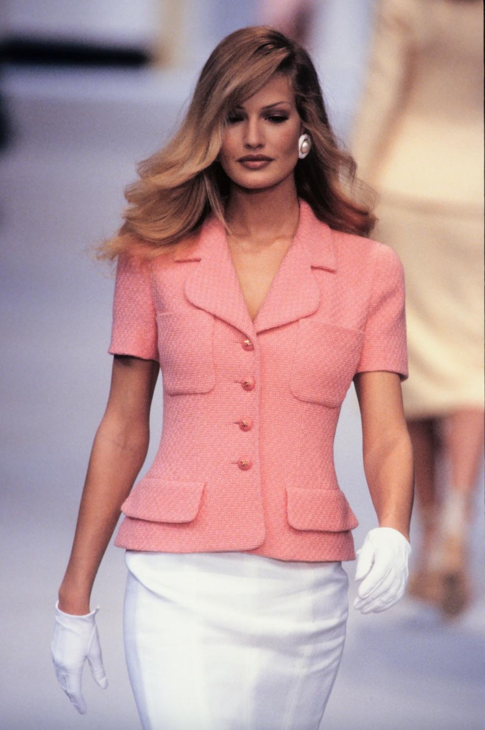 Presenting a pink short-sleeved jacket from Chanel's Spring/Summer 1993 collection. The jacket is crafted from textured cotton fabric and is adorned with the signature CC buttons, accompanied by four patch pockets. 
The jacket's exterior is