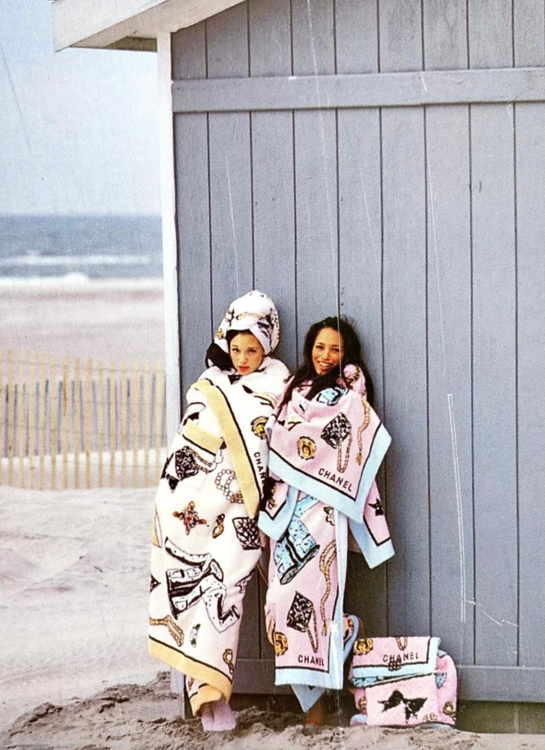This rare and iconic CHANEL beach towel from the Spring/Summer 1994 collection features a print of various classic Chanel items symbolizing the brand’s luxury and elegance, including accessories and motifs representing Chanel’s heritage. The towel