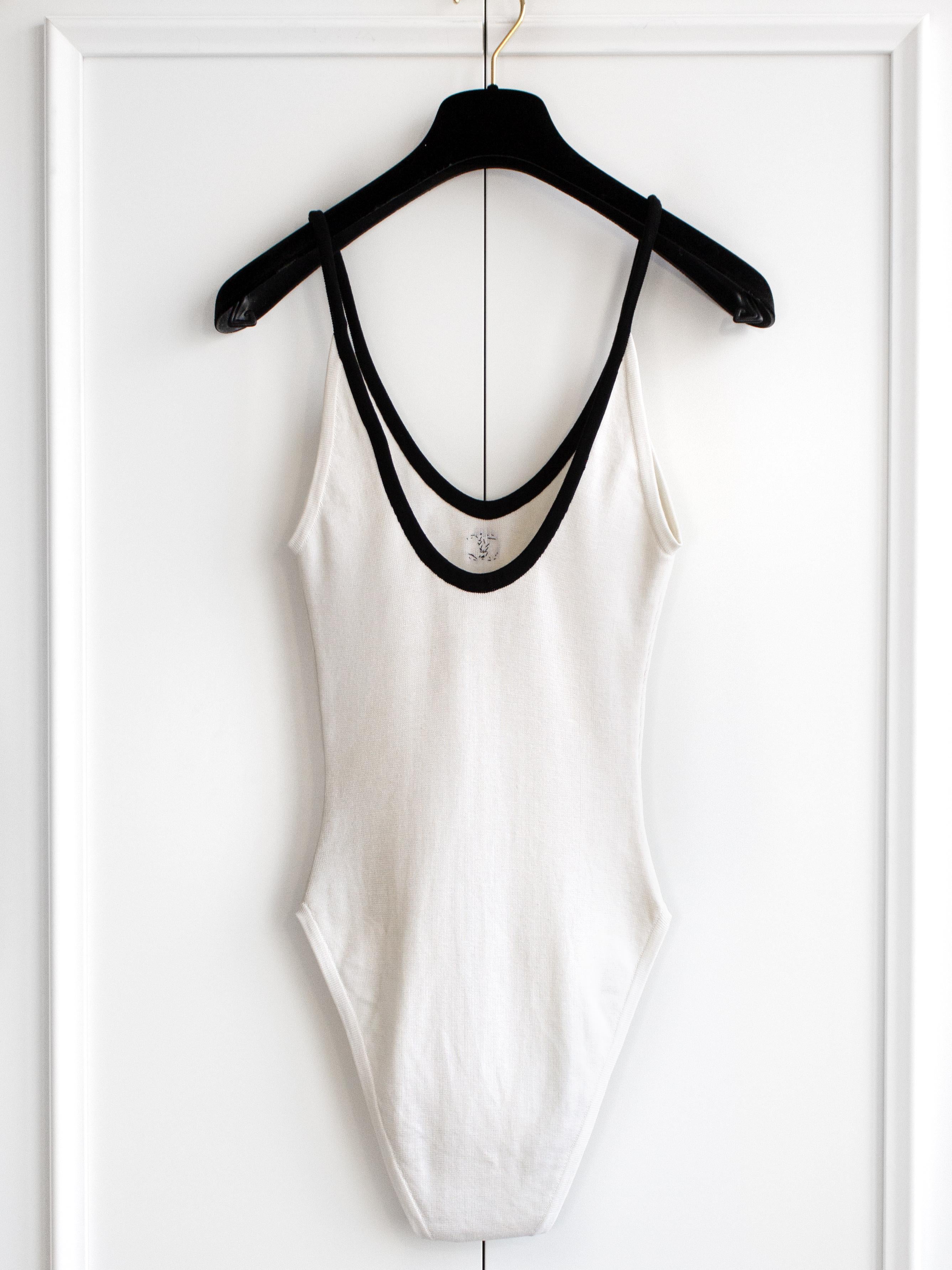 A scoop-neck white cotton bodysuit with a contrasting black trim and CC logo from Chanel Spring/Summer 1994 collection. Good condition, no visible flaws when worn but has stains on a crotch. The size and composition label is missing, best fits FR34.