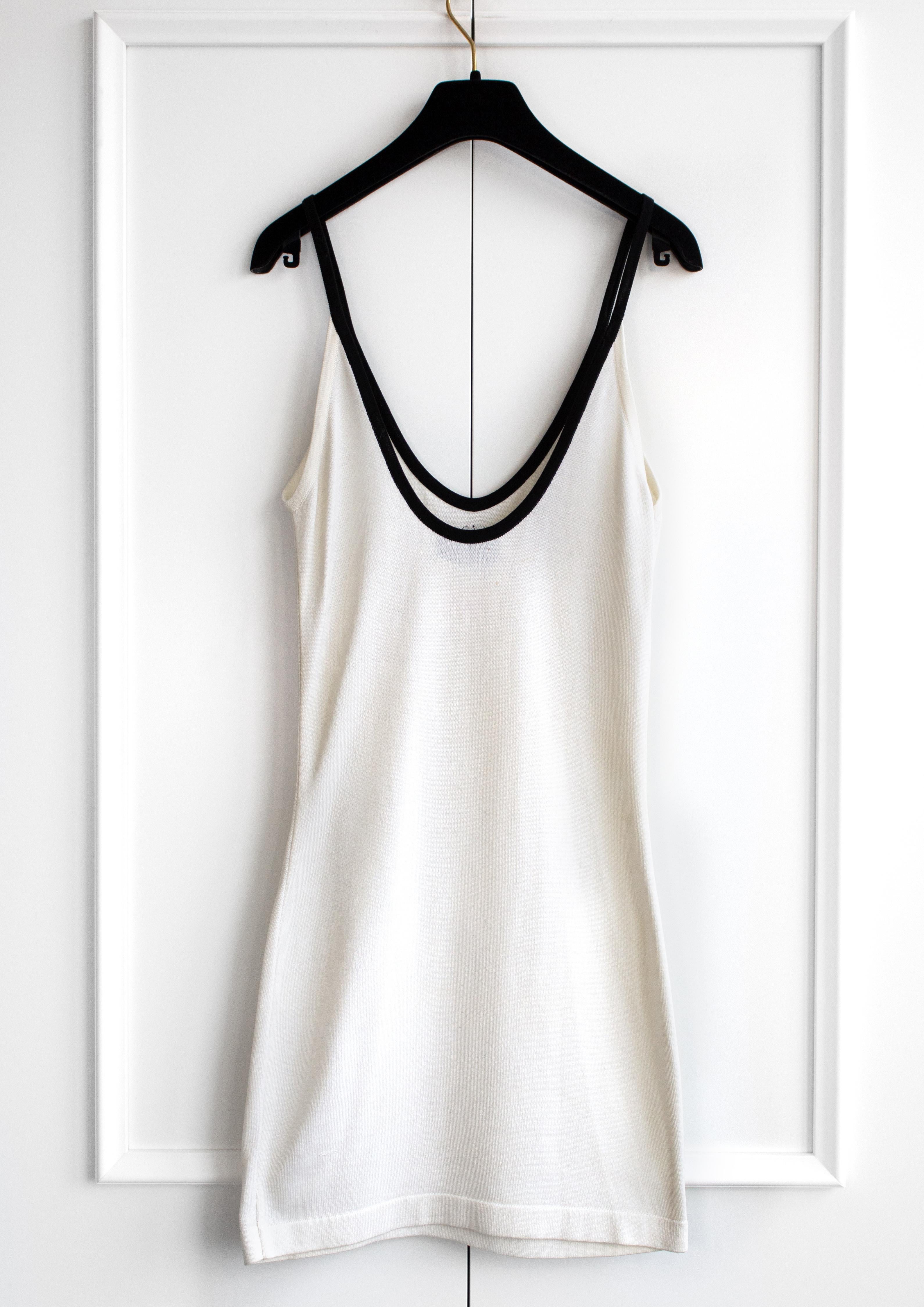 A classic scoop-neck white cotton mini dress with a contrasting black trim and CC logo from Chanel Spring/Summer 1994 collection. Very good condition, no major flaws except a couple tiny spots on the back. Size not listed, best fits FR34.