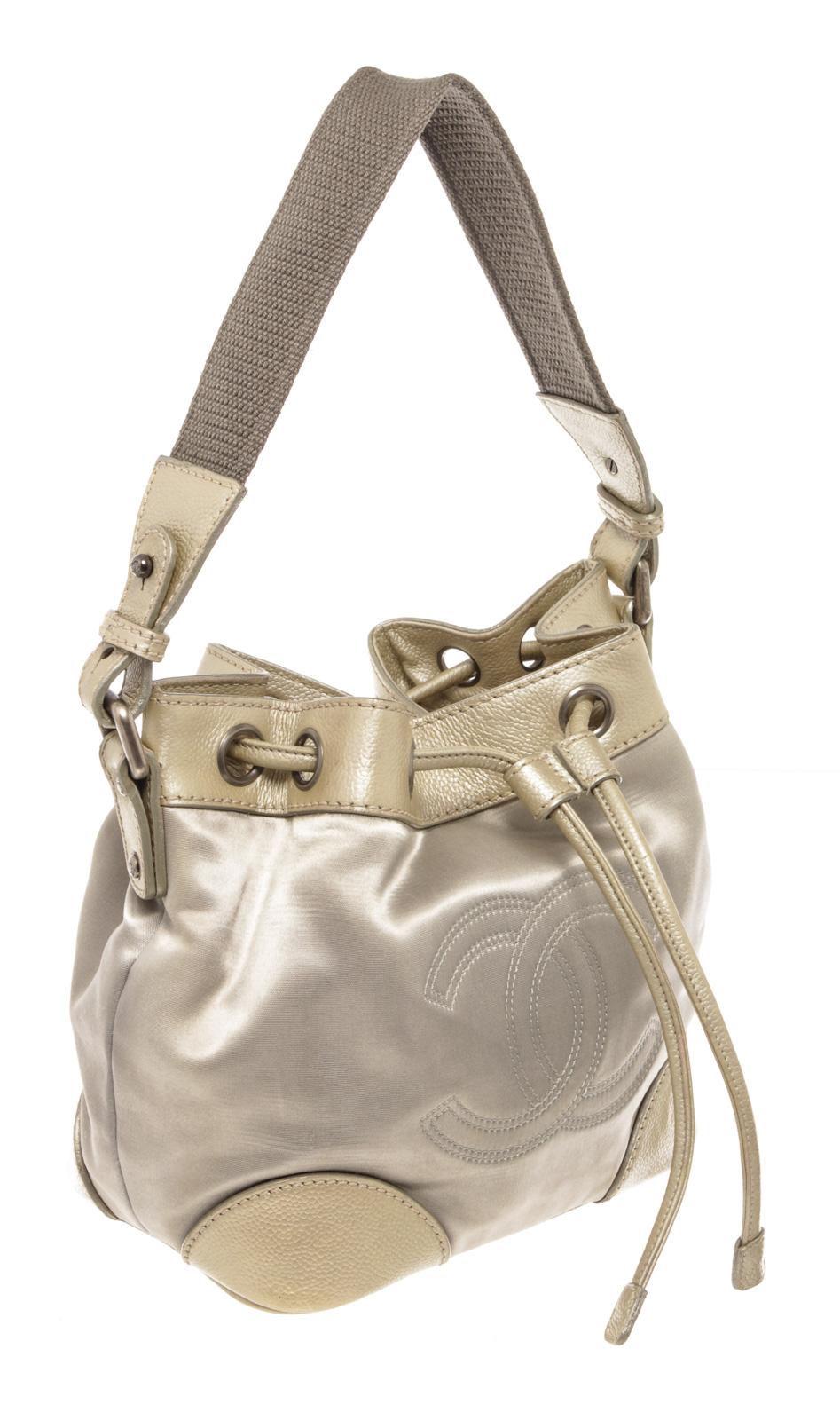 Metallic silver two-tone leather Chanel Vintage CC Drawstring bucket bag with silver-tone hardware, single leather top handle, an interlocking CC logo stitched at front, protective feet at base, drawsting closure at top that will open to beige