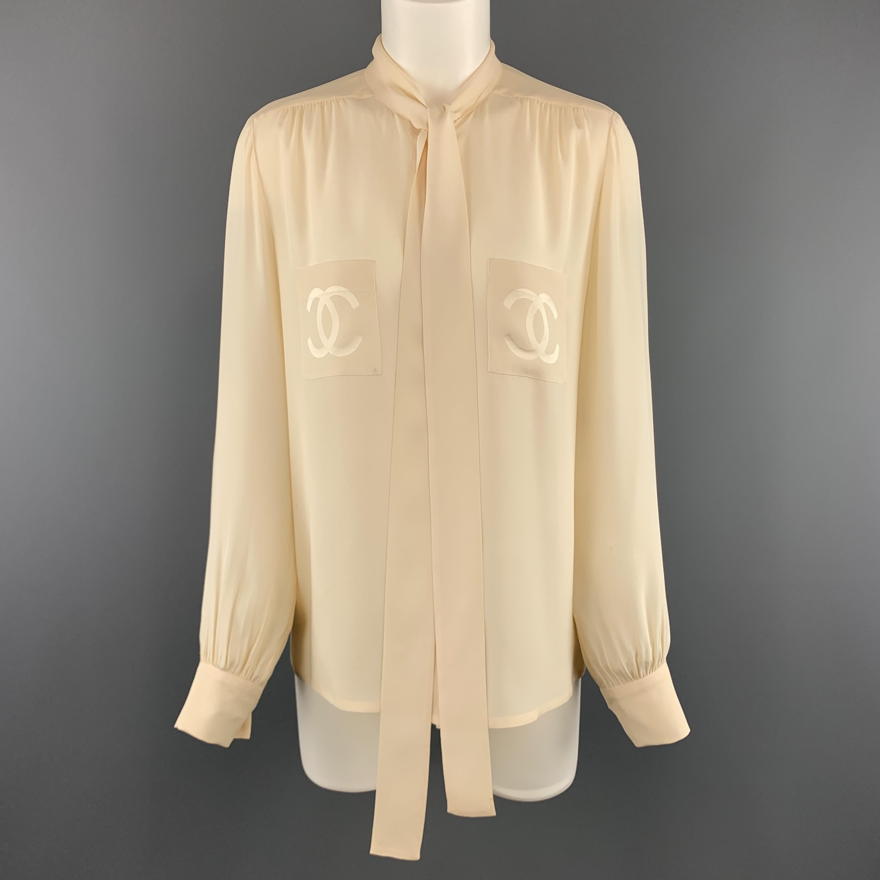 Vintage CHANEL blouse comes in creamy beige silk crepe with a tied collar, gathered shoulders and cuffs, and patch breast pockets with CC logo motifs. spots and wear throughout. As-is. Made in France.

Good Pre-Owned Condition.
Marked: FR