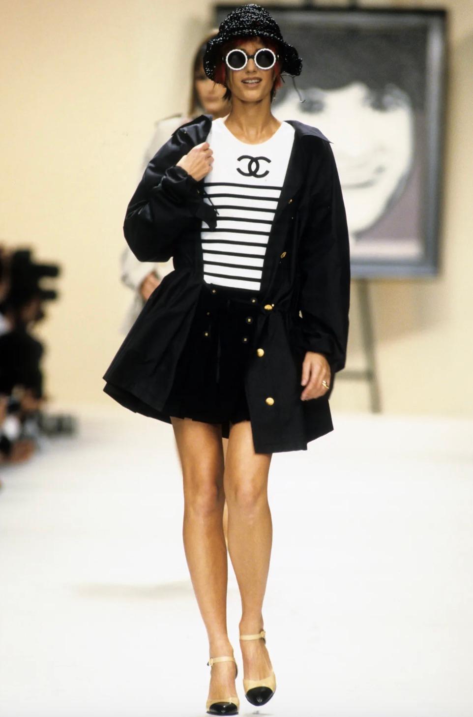 This white/black top from Chanel's Spring/Summer 1994 collection is a chic and timeless piece. Crafted from lightweight pure cotton, the knit fabric comes in optic white adorned with an embroidered logo over horizontal stripes. It has a round neck,