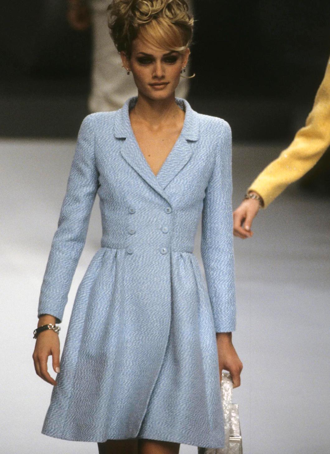 This pretty Chanel coat from the Spring/Summer 1996 collection, famously worn by Amber Valletta, is a stunning piece crafted from baby blue cotton tweed. It boasts a double-breasted design adorned with matching blue CC logo buttons. The luxurious