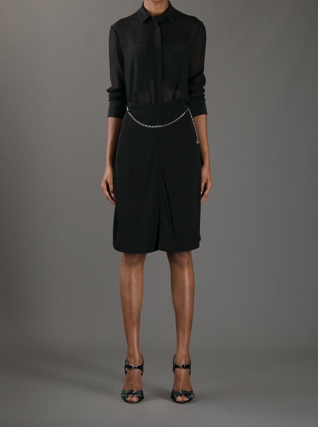 The Chanel Spring/Summer 1997 classic black skirt is knee-length, featuring a built-in gold-tone metal and leather chain at the waist, accented with the signature CC logo medallion.
In very good condition with no obvious signs of wear. Labeled in