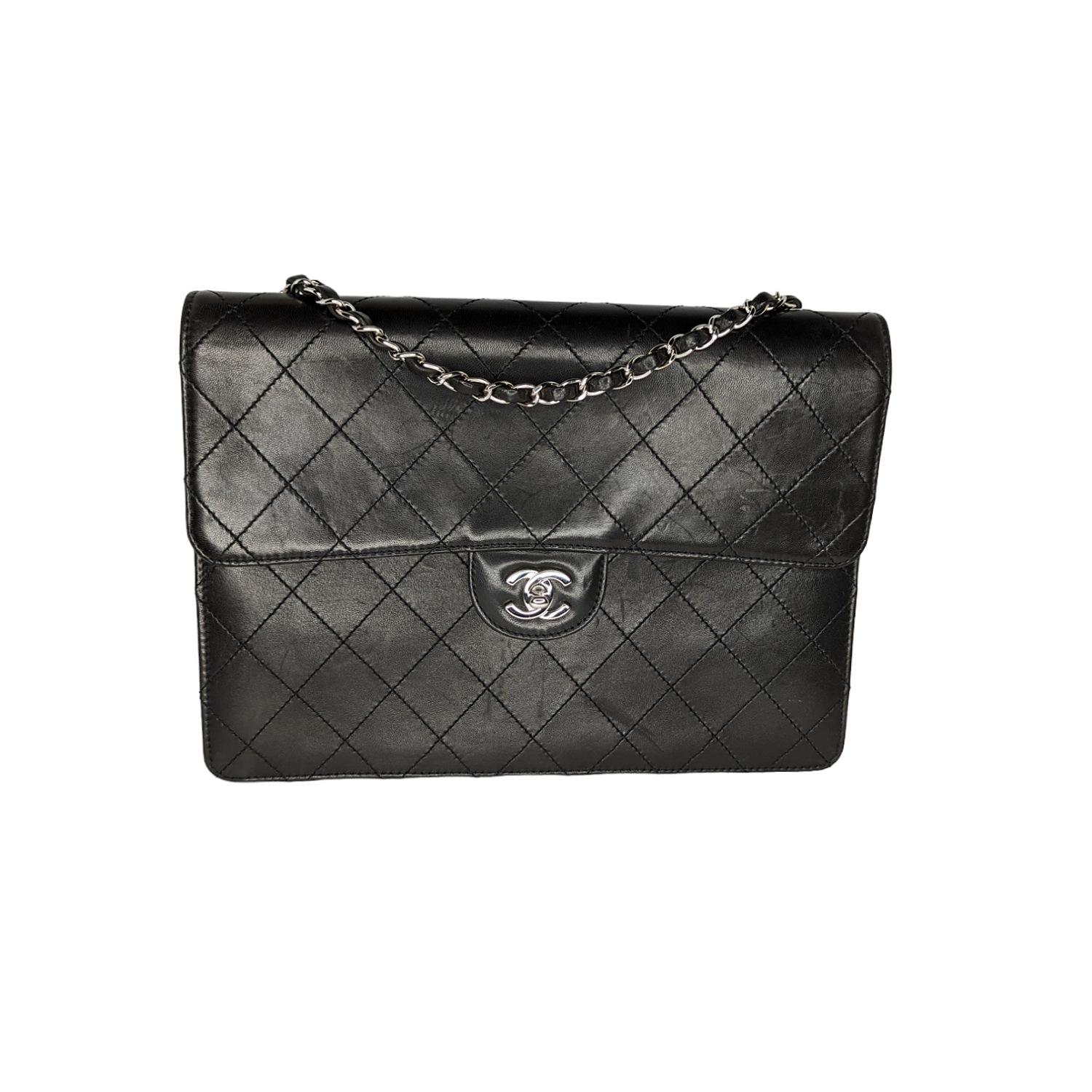 This classic bag is finely composed of luxurious diamond quilted lambskin leather. The bag features a silver chain link leather threaded shoulder strap and a silver Chanel CC turn lock. This opens the front flap to a leather interior with a zipper