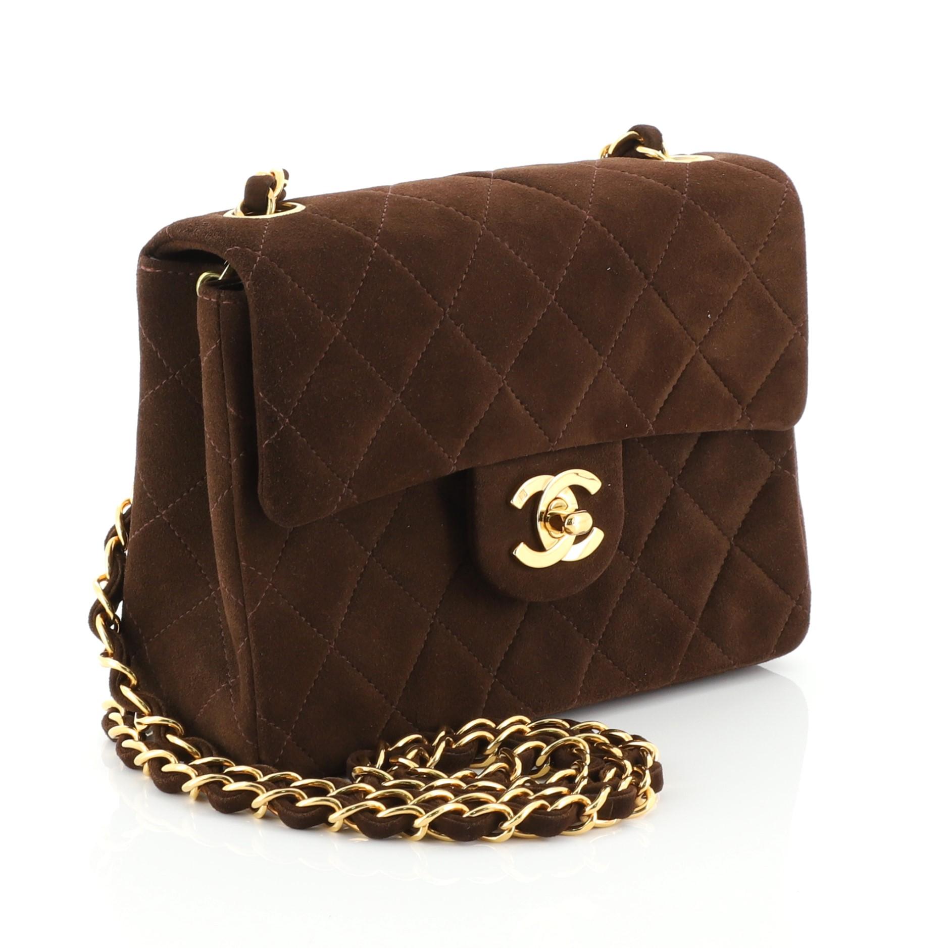 This Chanel Vintage Square Classic Single Flap Bag Quilted Suede Mini, crafted from brown quilted suede, features woven-in chain link straps, a structured silhouette, and gold-tone hardware. Its CC turn-lock closure opens to a brown leather interior