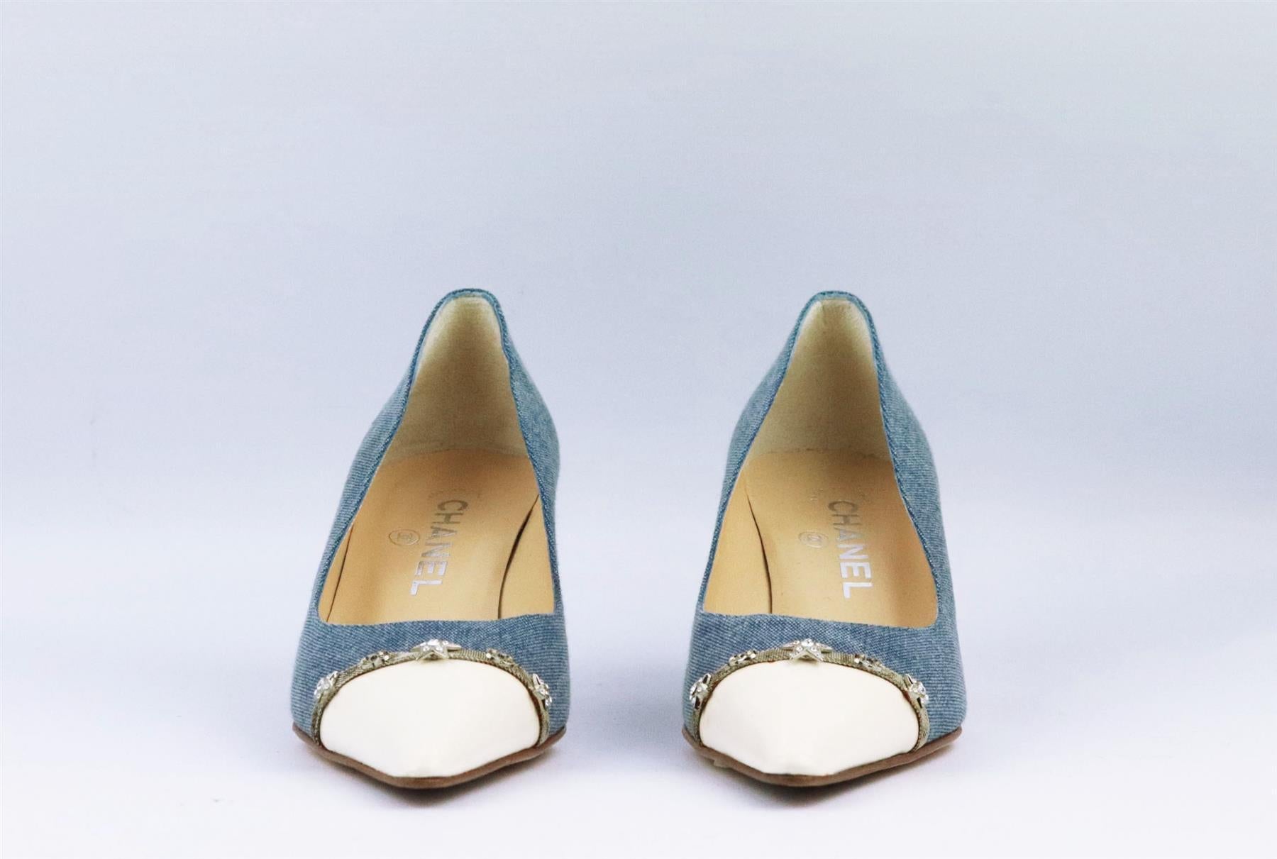 These vintage pumps by Chanel have been made in Italy from blue denim, they're set on a small structured stiletto heel that's balanced with a white leather pointed toe cap and studded with silver tone star and CC on the front. Heel measures