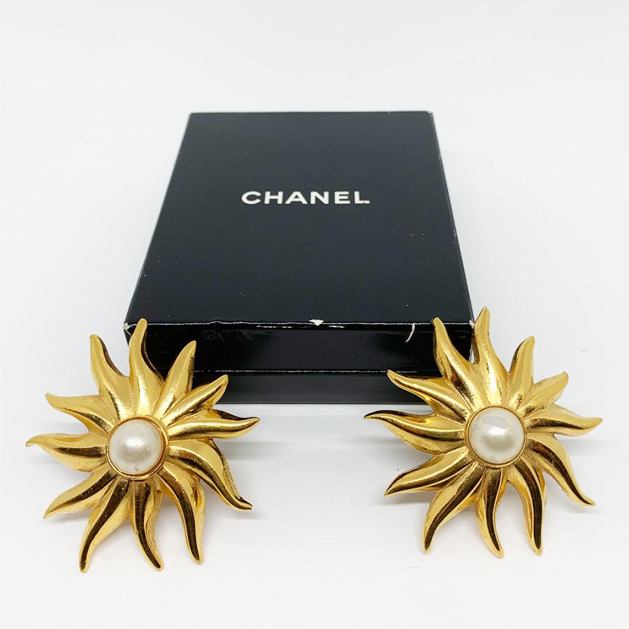 Put some sun in your life with this pair of vintage clip earrings from Maison CHANEL. Each represents a blazing sun in metal gilded with fine gold, with a pearly pearl at its heart. For a sophisticated and trendy look!
The earrings are in good