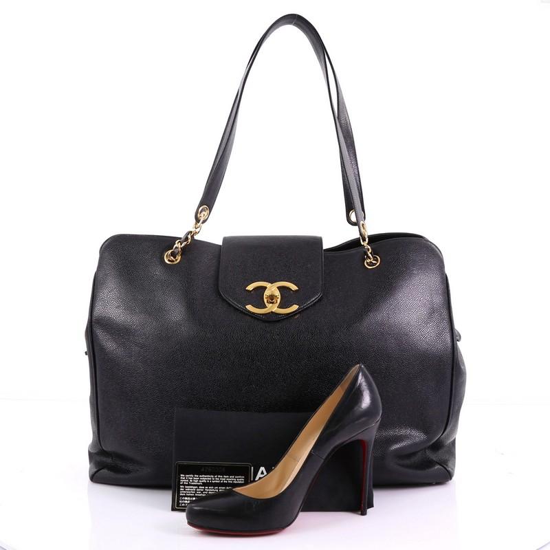 This Chanel Vintage Supermodel Weekender Bag Caviar Large, crafted in black caviar leather, features dual leather strap with chain links and gold-tone interior. Its CC turn-lock closure opens to a black fabric interior with zip pockets. Hologram