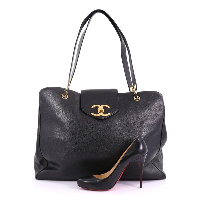 This Chanel Vintage Supermodel Weekender Bag Caviar Large, crafted in black caviar leather, features dual leather straps with chain links and gold-tone hardware. Its CC turn-lock closure opens to a black fabric interior with zip pockets. Hologram