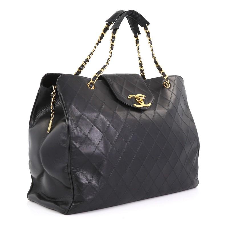 This Chanel Vintage Supermodel Weekender Bag Quilted Leather Large, crafted in black quilted leather, features dual woven-in leather chain straps, flap tab with turn-lock closure, and gold-tone hardware. Its zip closure opens to a black leather