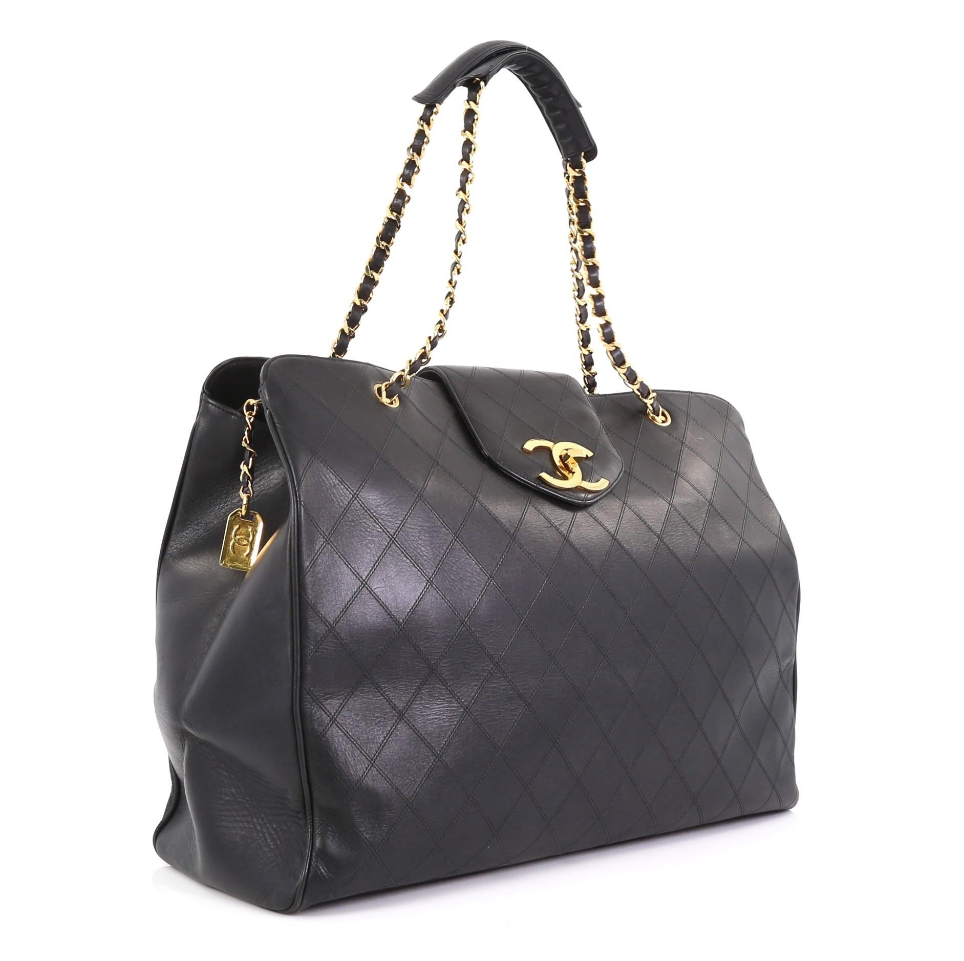 This Chanel Vintage Supermodel Weekender Bag Quilted Leather Large, crafted in black quilted leather, features dual woven-in leather chain straps, flap tab with turn-lock closure, and gold-tone hardware. Its zip closure opens to a black leather