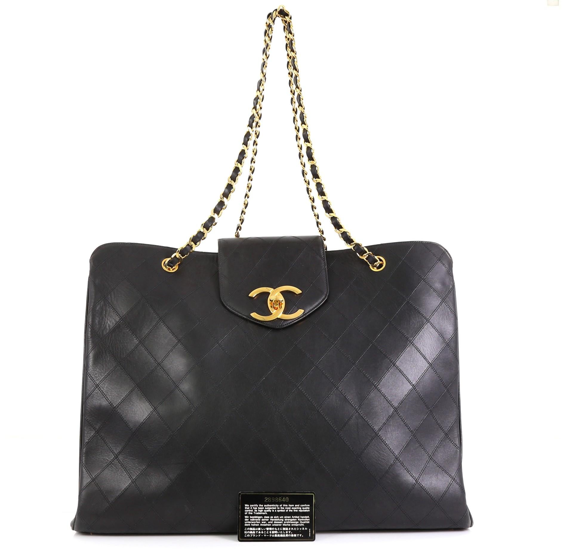 This Chanel Vintage Supermodel Weekender Bag Quilted Leather Large, crafted in black quilted leather, features dual woven-in leather chain straps, flap tab with turn-lock closure, and gold-tone hardware. Its zip closure opens to a black leather