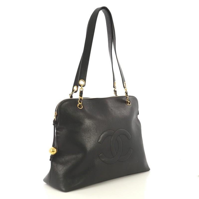 This Chanel Vintage Timeless Zip Tote Caviar Large, crafted from black caviar leather, features woven-in leather chain straps with shoulder pads, CC stitched logo at front, and gold-tone hardware. Its zip closure opens to a black satin interior with