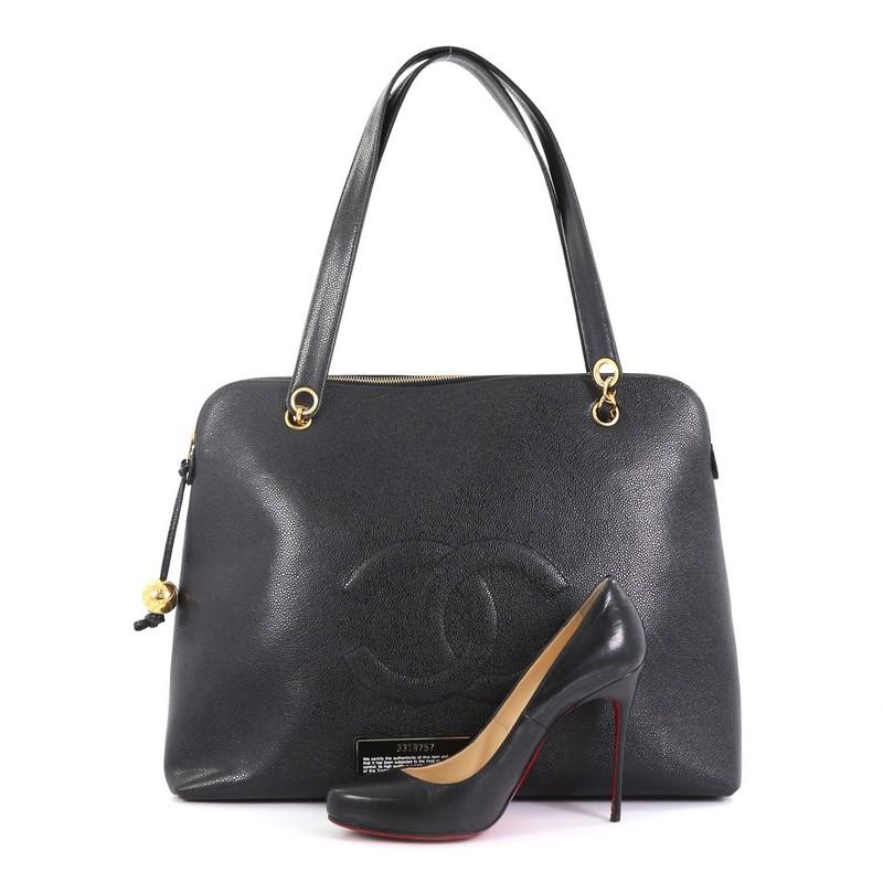 This Chanel Vintage Timeless Zip Tote Caviar Large, crafted from black caviar leather, features woven-in leather chain straps with shoulder pads, CC stitched logo at front, and gold-tone hardware. Its zip closure opens to a black satin interior with