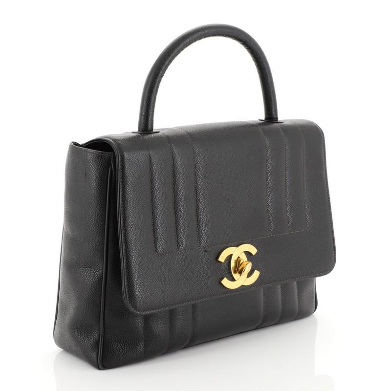 This Chanel Vintage Top Handle Bag Vertical Quilt Caviar Jumbo, crafted in black vertical quilted caviar leather, features rolled top handle and gold-tone hardware. Its CC turn-lock closure opens to a black leather interior with side zip and slip