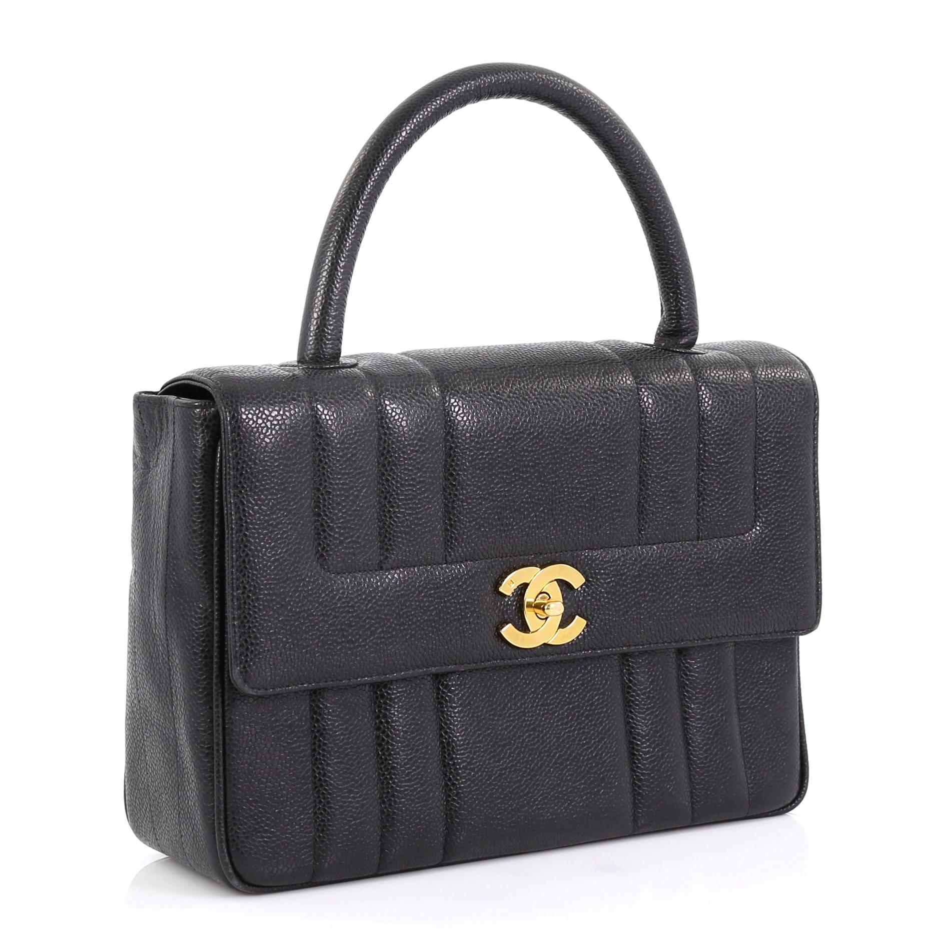 This Chanel Vintage Top Handle Bag Vertical Quilt Caviar Medium, crafted in black vertical quilted caviar leather, features rolled top handle and gold-tone hardware. Its CC turn-lock closure opens to a black leather interior with side zip and slip