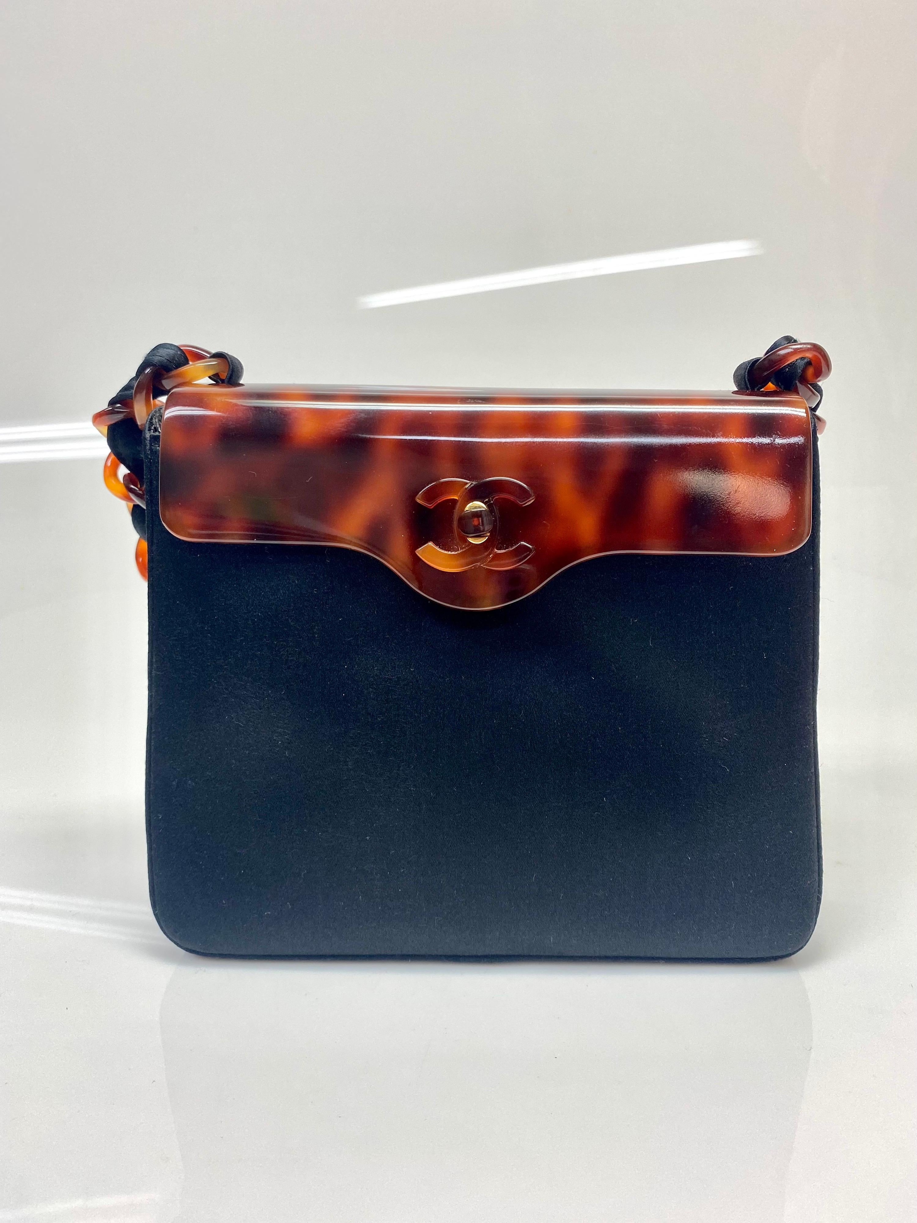 This authentic Chanel black silk tortoiseshell detail evening bag is a rare and stunning addition for any collection.  The bag features the iconic CC logo, and a magnetic opening. The strap is linked detailing with black silk and tortoiseshell woven