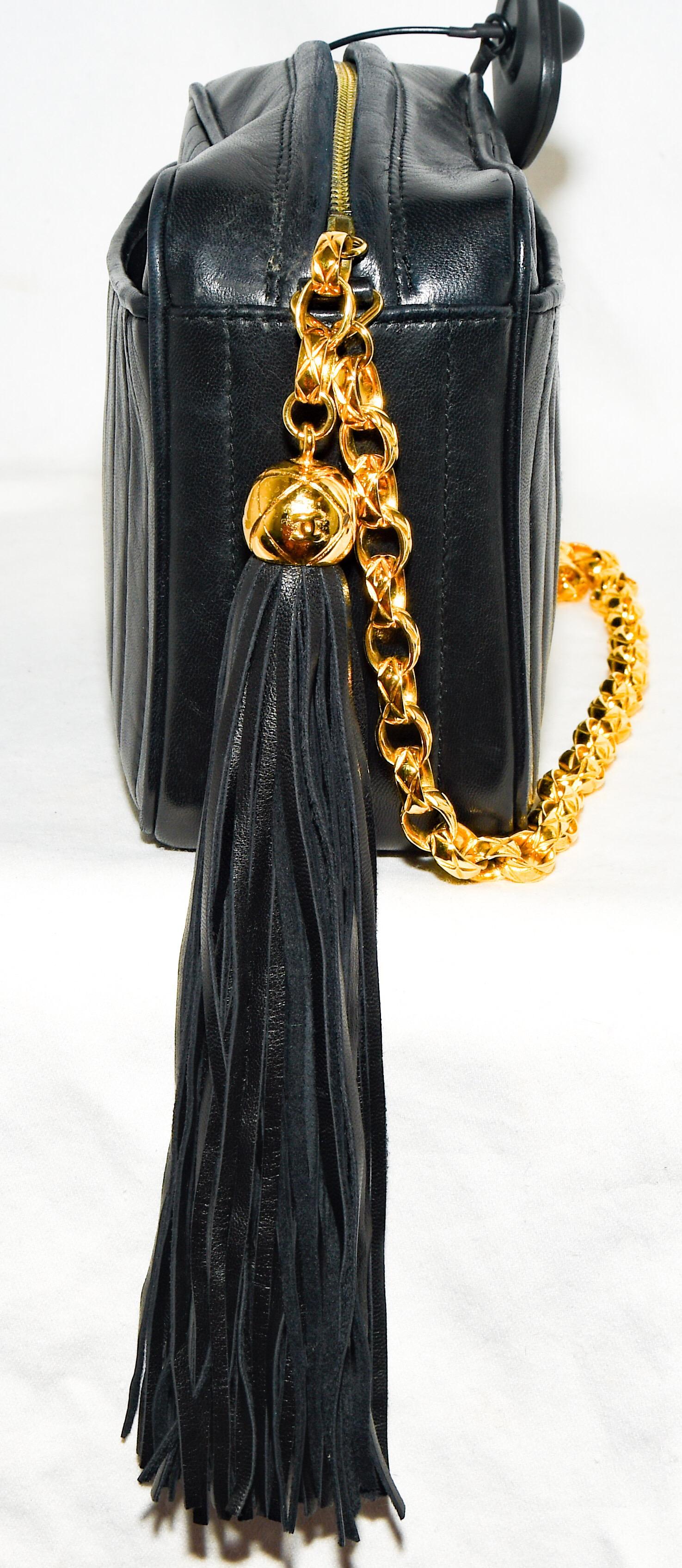 Chanel vintage, from the 1990's, vertical quilt camera bag in soft lambskin black leather contains two patch pockets,  on both front and back of bag.  With a metal quilted Chanel CC logo zipper pull on the leather tassel, for closure.    The front