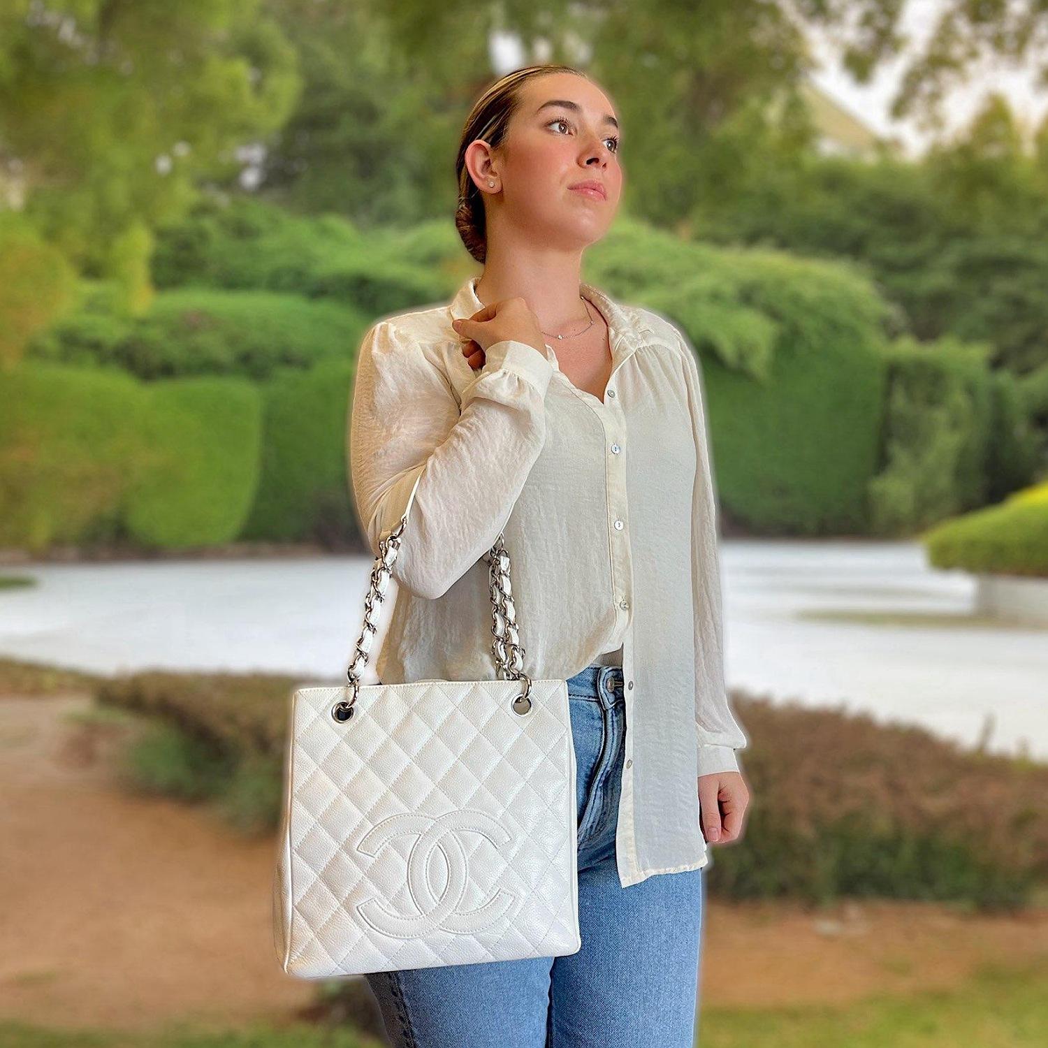 This Chanel Petite Shopping Tote is crafted of white caviar leather and features a variety of pockets for easy and simple organization of your daily necessities. The two handles are made of silver-tone chain with interwoven white leather for a soft