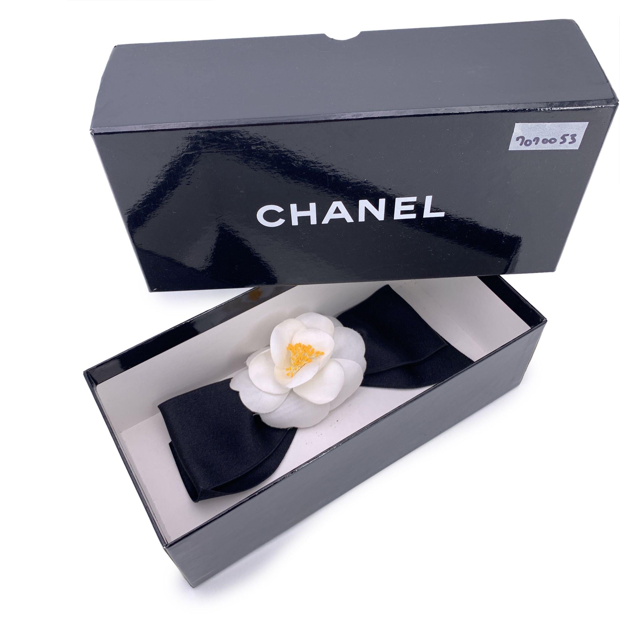 Lovely vintage Chanel brooch. White silk Camellia flower with black satin bow 'Chanel CC Made in France' oval tab on the back. Flower width: 3.5 inches - 8.9 cm. Height: 3.5 inches - 8.9 cm. Bow width: 7.5 inches - 19 cm Condition A - EXCELLENT