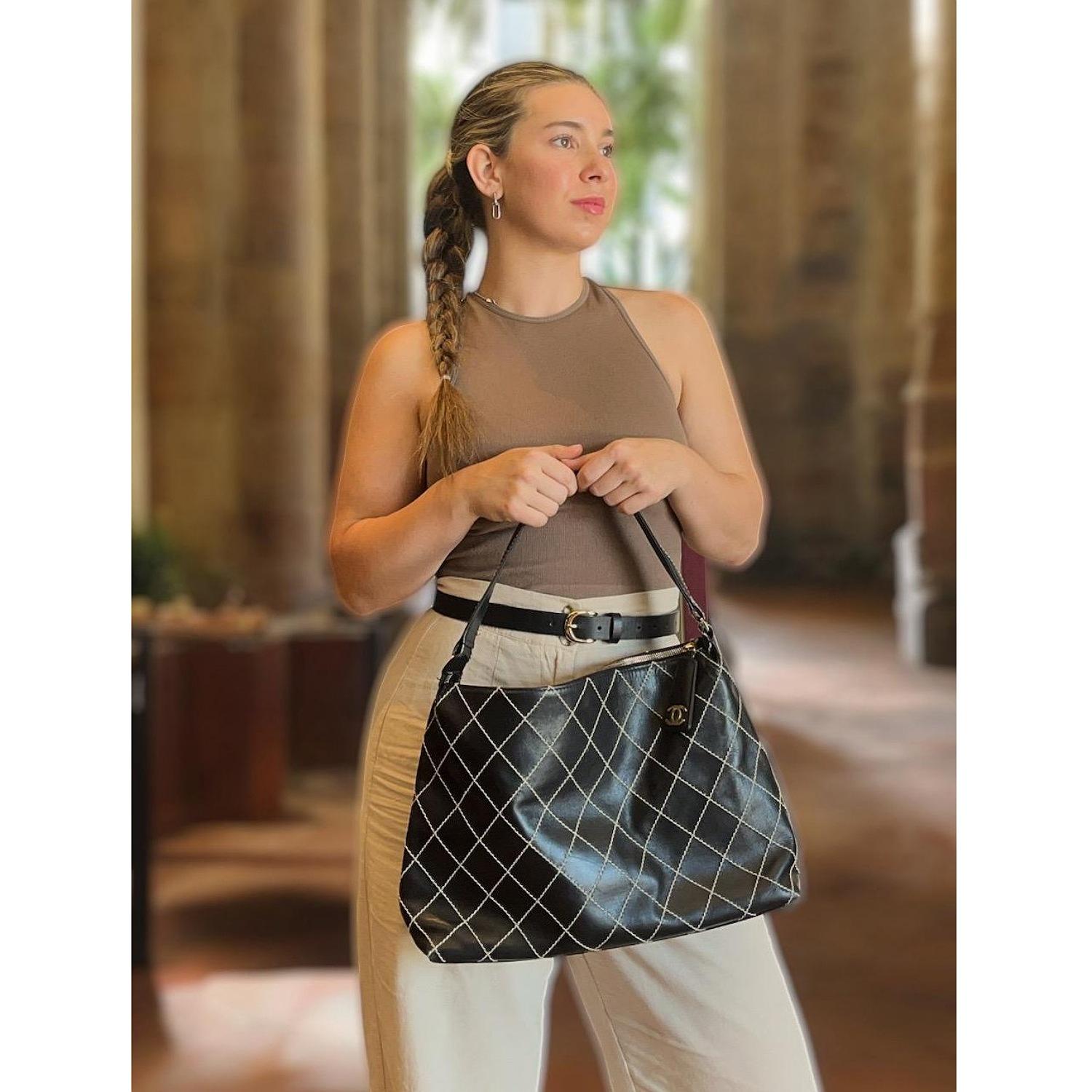 Up for sale is a Chanel Wild Stitch Hobo Shoulder Bag from the 2002-2003 Collection by Karl Lagerfeld. This timeless bag is crafted from black calfskin leather and features a unique wild stitch design. The bag has a zip closure at the top, gold-tone