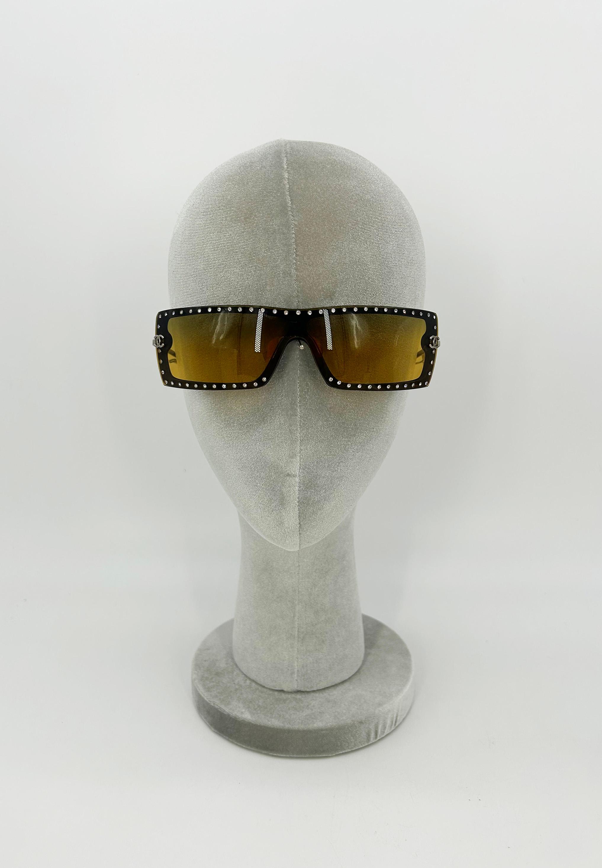 Lunettes de soleil Chanel Vintage CC Logo Brown Crystal Frame Shield c2000s en excellent état. Lentilles rectangulaires marron avec de minuscules cristaux de strass entourant les bords extérieurs de la lentille. Breloque argentée du logo CC