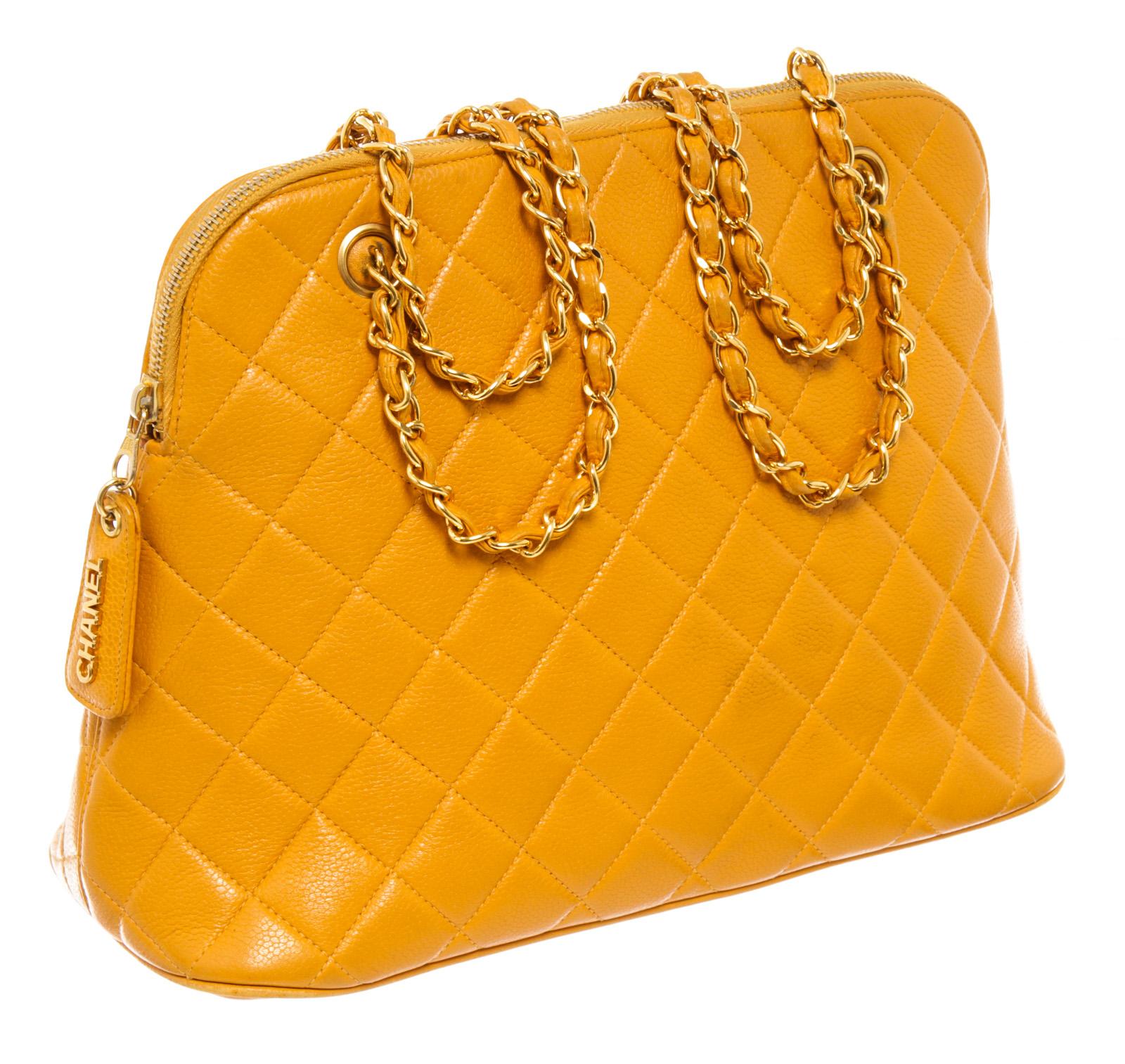 Chanel Matelasse Shoulder Bag in yellow quilted Caviar leather and has gold-tone hardware. It has a unique rounded top shape with a wrap-around zipper closure. The zipper has a stylish zipper tag with 