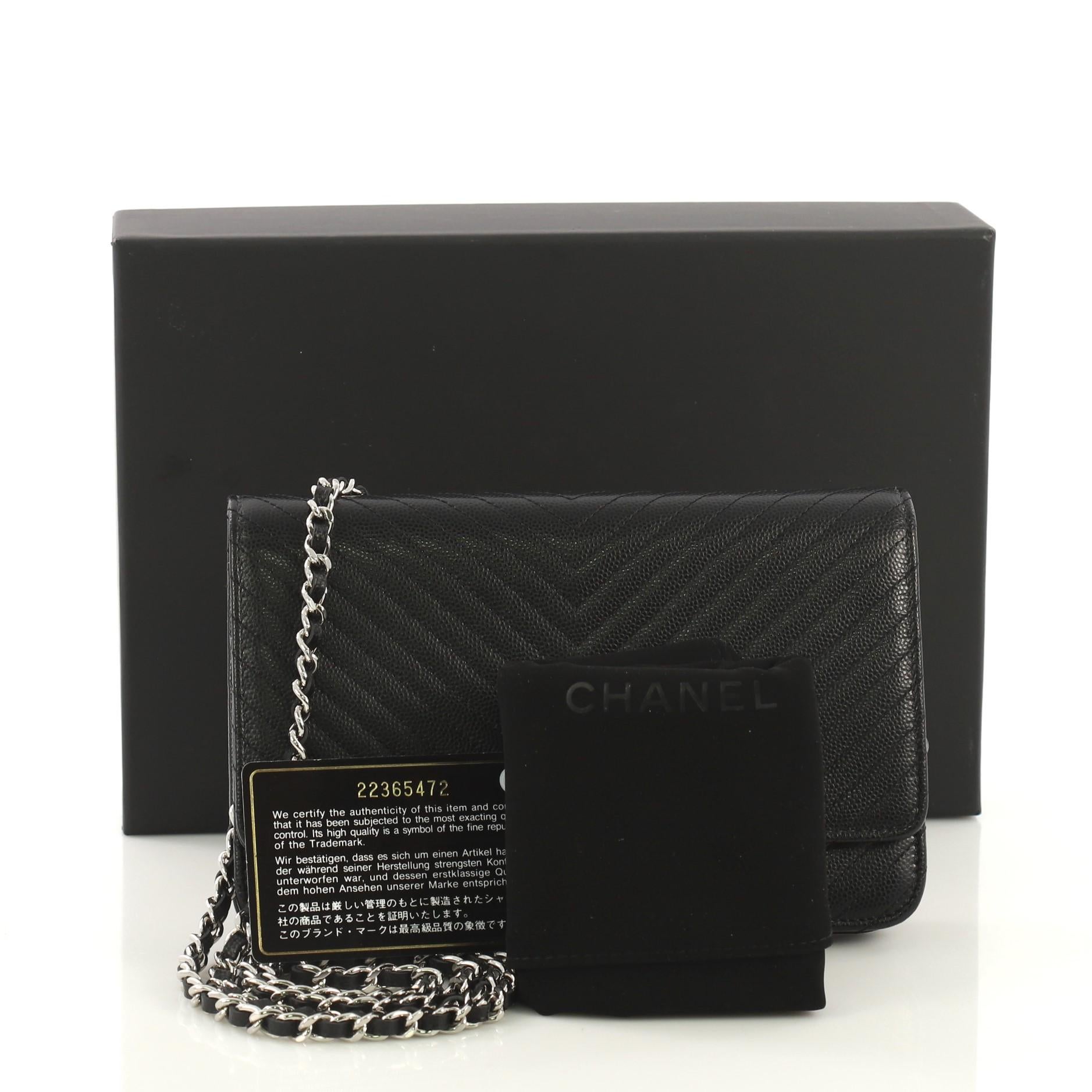 This Chanel Wallet on Chain Chevron Caviar, crafted from black chevron caviar leather, features woven-in leather chain strap, interlocking CC logo on its flap, back slip pocket, and silver-tone hardware. Its hidden snap closure opens to a burgundy