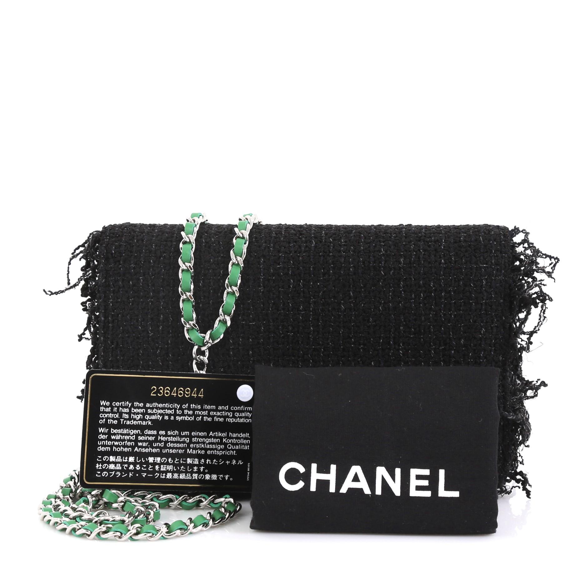 This Chanel Wallet on Chain Fringe Tweed, crafted in black fringe tweed, features woven-in leather chain strap, CC logo at front flap and silver-tone hardware. Its magnetic snap button closure opens to a green fabric interior with multiple card