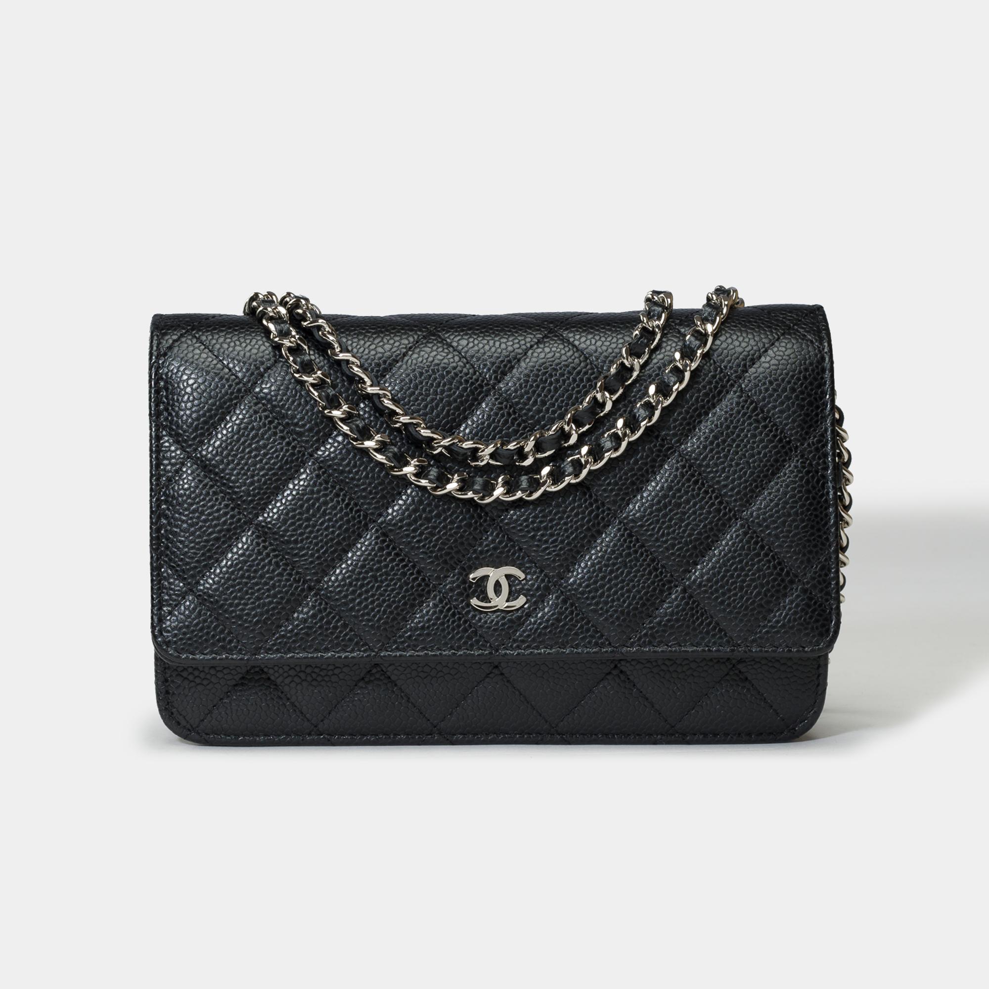 Magnifique sac à bandoulière Chanel Wallet On Chain (WOC) en cuir caviar matelassé noir, garniture en métal argenté, chaîne en métal argenté entrelacée de cuir noir permettant un portage à l'épaule ou en bandoulière.

Une poche plaquée au dos du