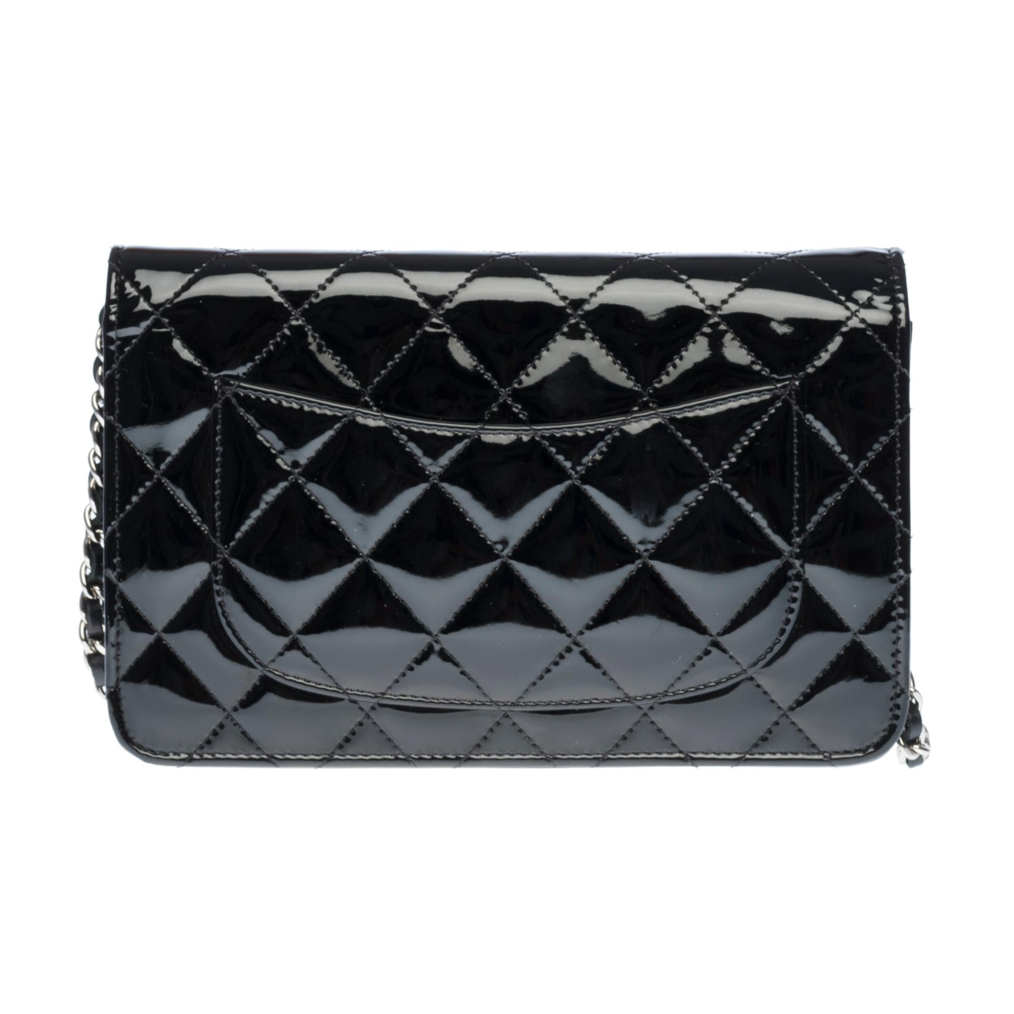 Lovely Chanel Wallet on Chain (WOC) shoulder bag in black quilted patent leather, silver metal trim, a silver metal chain handle intertwined with black leather allowing a shoulder or shoulder strap.

Closure by flap.
Black leather lining, one zip