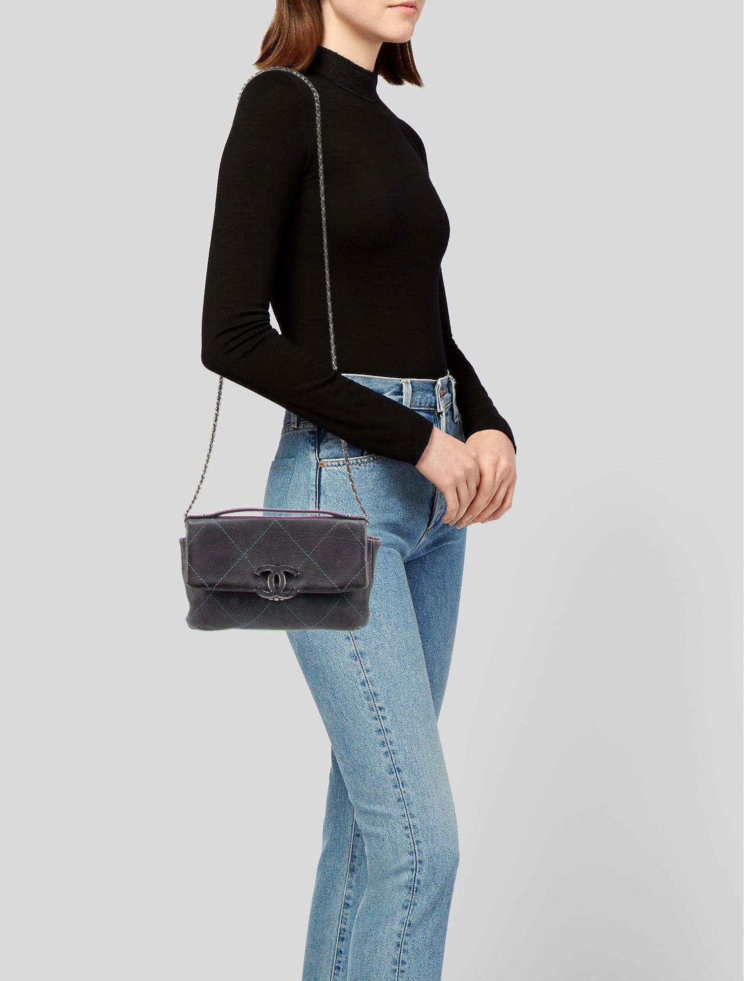 This Chanel shoulder bag is constructed of blue and black calfskin and features blue diamond-stitched quilting, black and silver-tone hardware, an interlocking CC detail, and a chain-link shoulder strap. The front flap is secured with a clasp