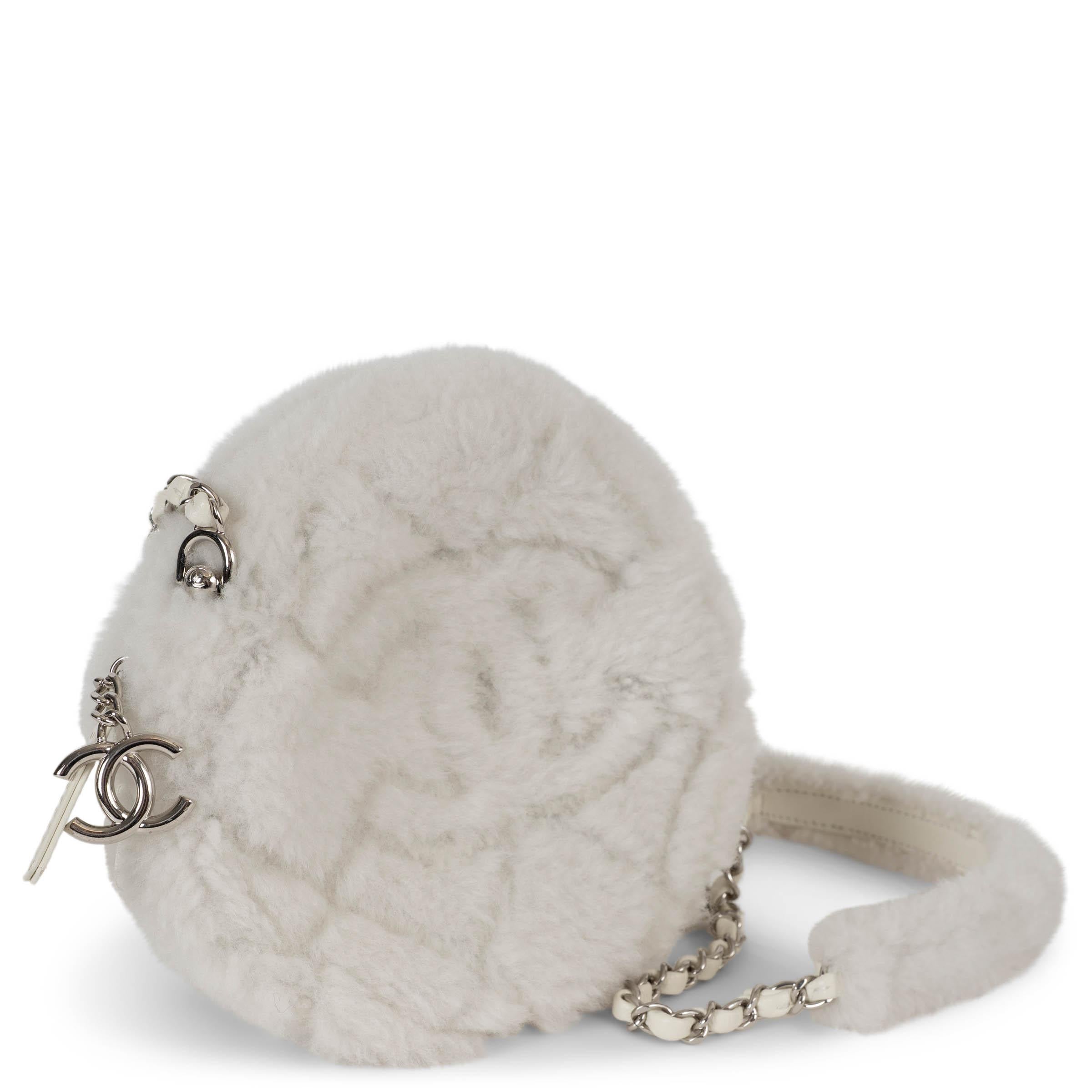 Cet étui rond 100 % authentique de Chanel est fabriqué en peau d'agneau blanche et pelucheuse, et est rehaussé de ferrures argentées pour une allure hivernale audacieuse. Ce modèle ludique arbore le logo CC emblématique et les détails matelassés