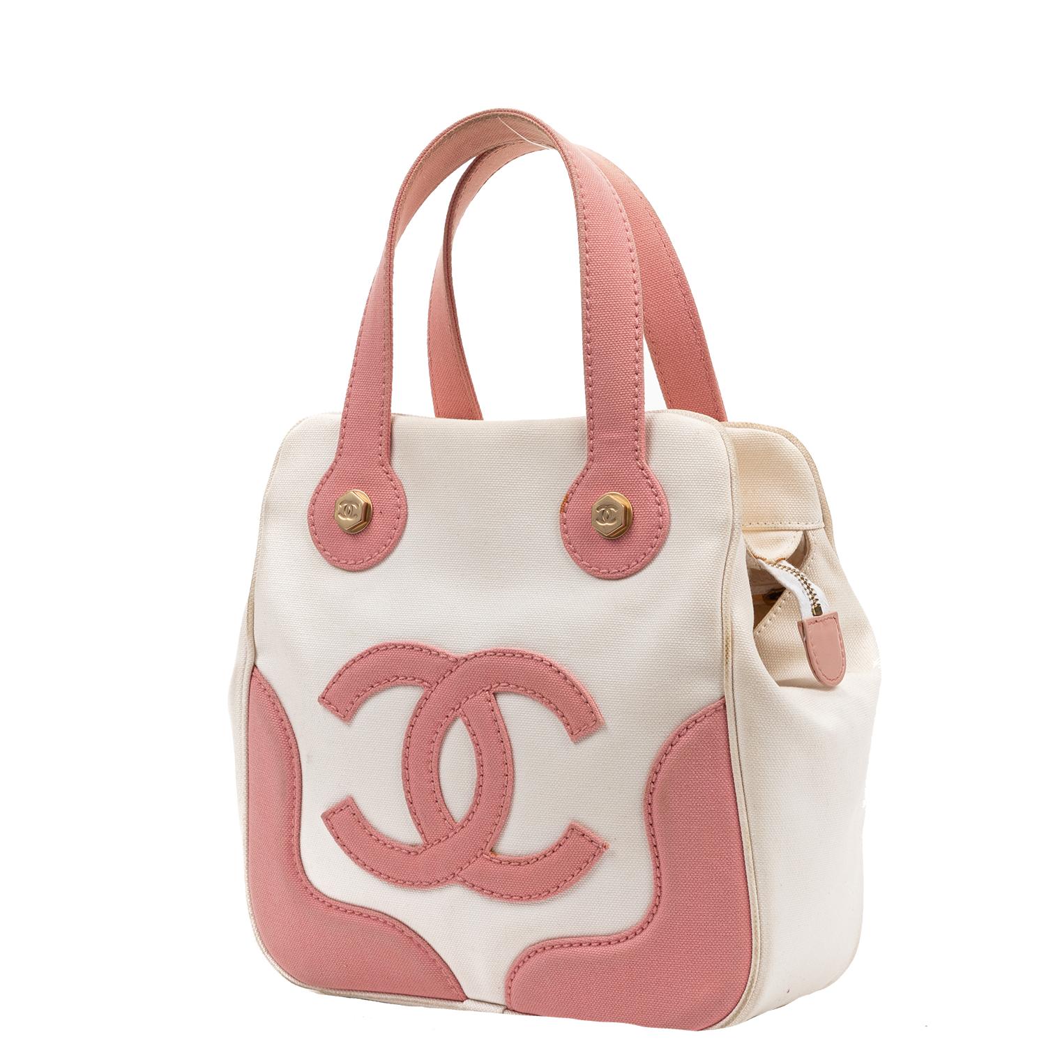 Extremely rare and fun early 2000s vintage tote!!! This adorable Chanel is crafted in white and pink canvas, brushed gold-tone hardware, and a super fun pink CC canvas logo to the front face. There are dual flat handles and protective legs at the