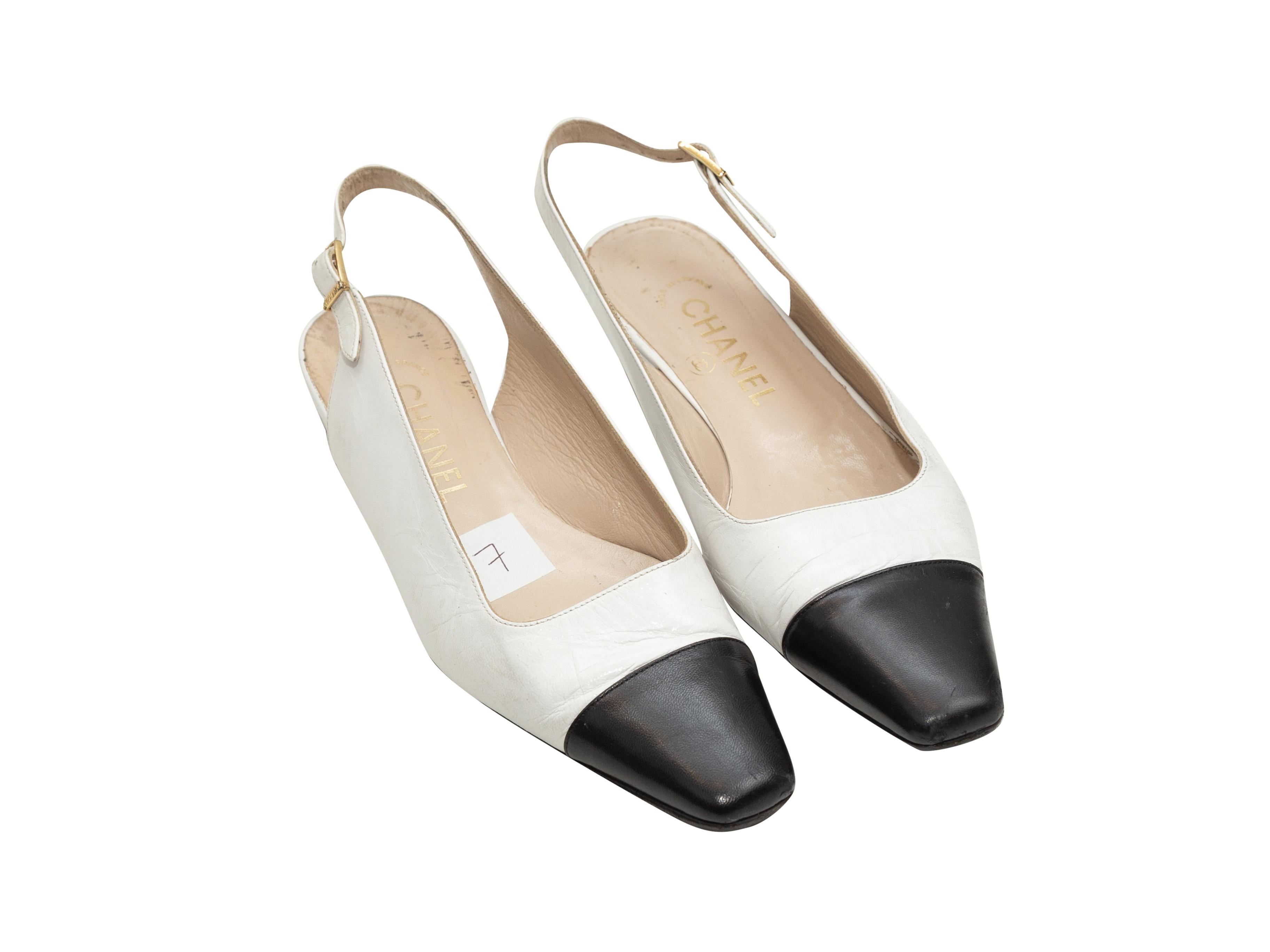 Product details: Vintage white and black leather cap-toe slingback flats by Chanel. Gold-tone buckle closures at slingback straps. Designer size 37. 1