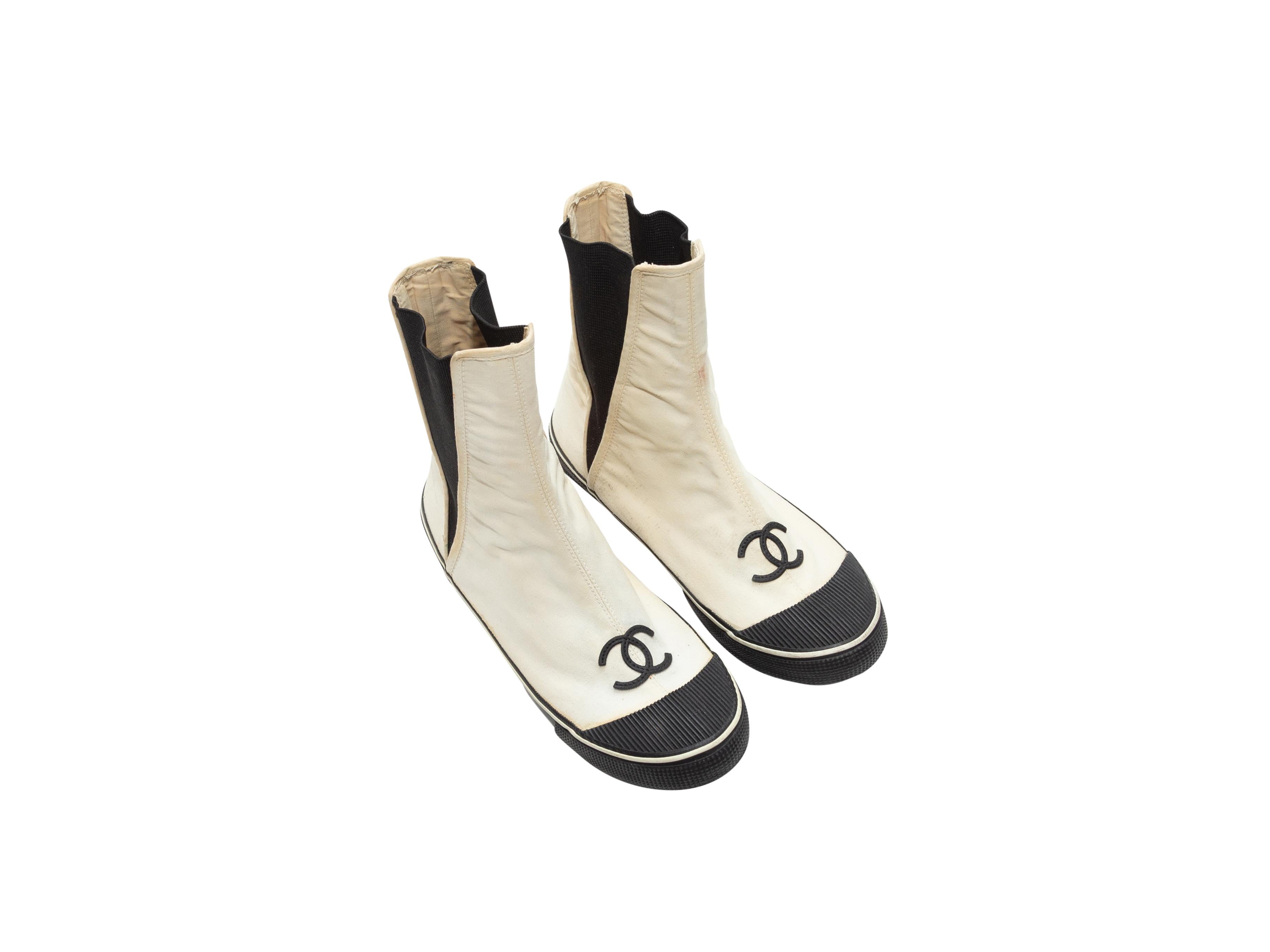 Product details: Vintage white canvas and black rubber flat boots by Chanel. Cap-toes. CC logos at toes. Elasticized side gores. Rubber soles. 4.5