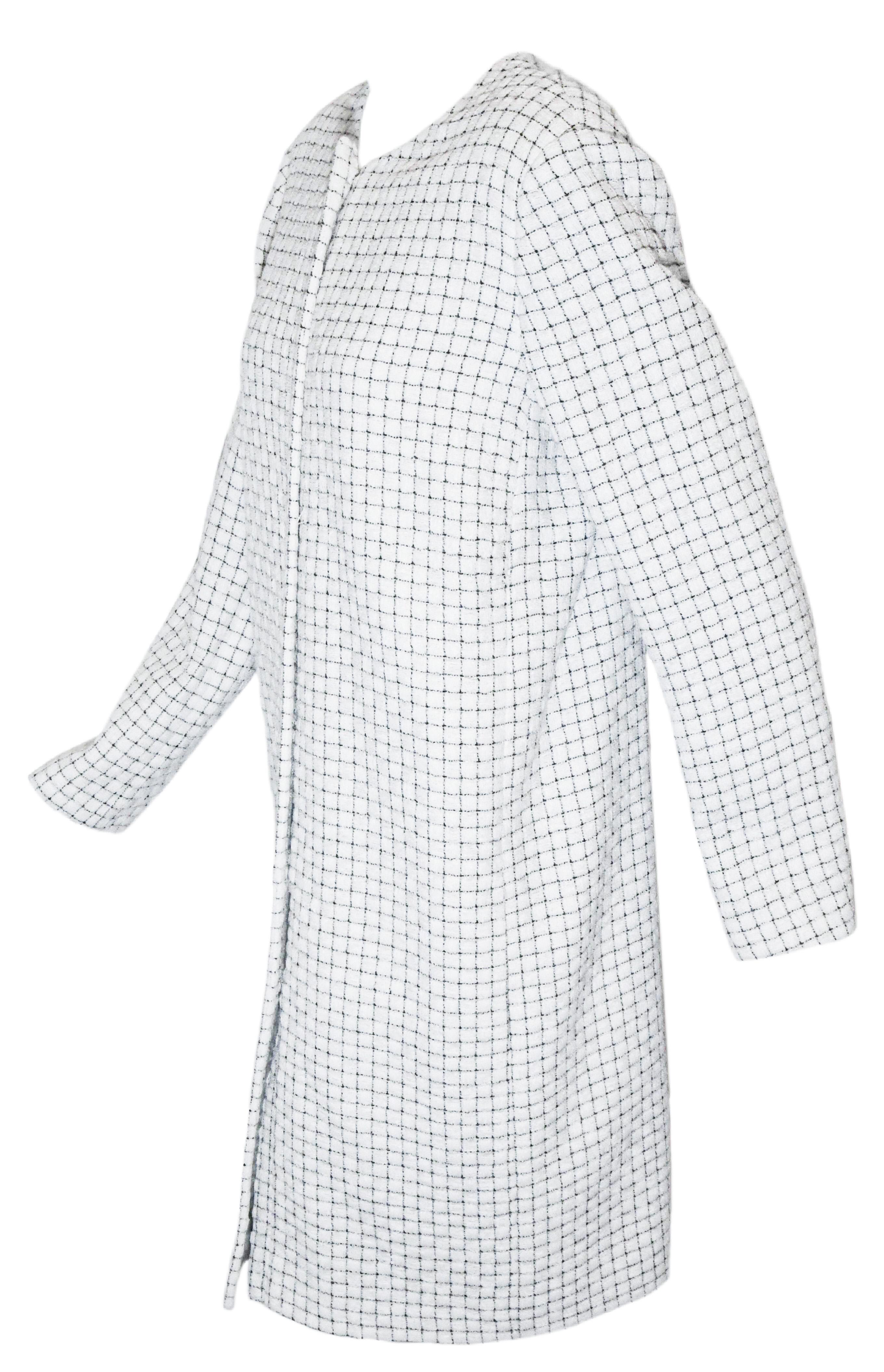 Chanel white and black check coat from the Spring 2016 Collection is a contemporary, modern long jacket/coat. This fantasy tweed white coat with black thin trim creating the check pattern allover the coat is in pristine condition.  It is lined in
