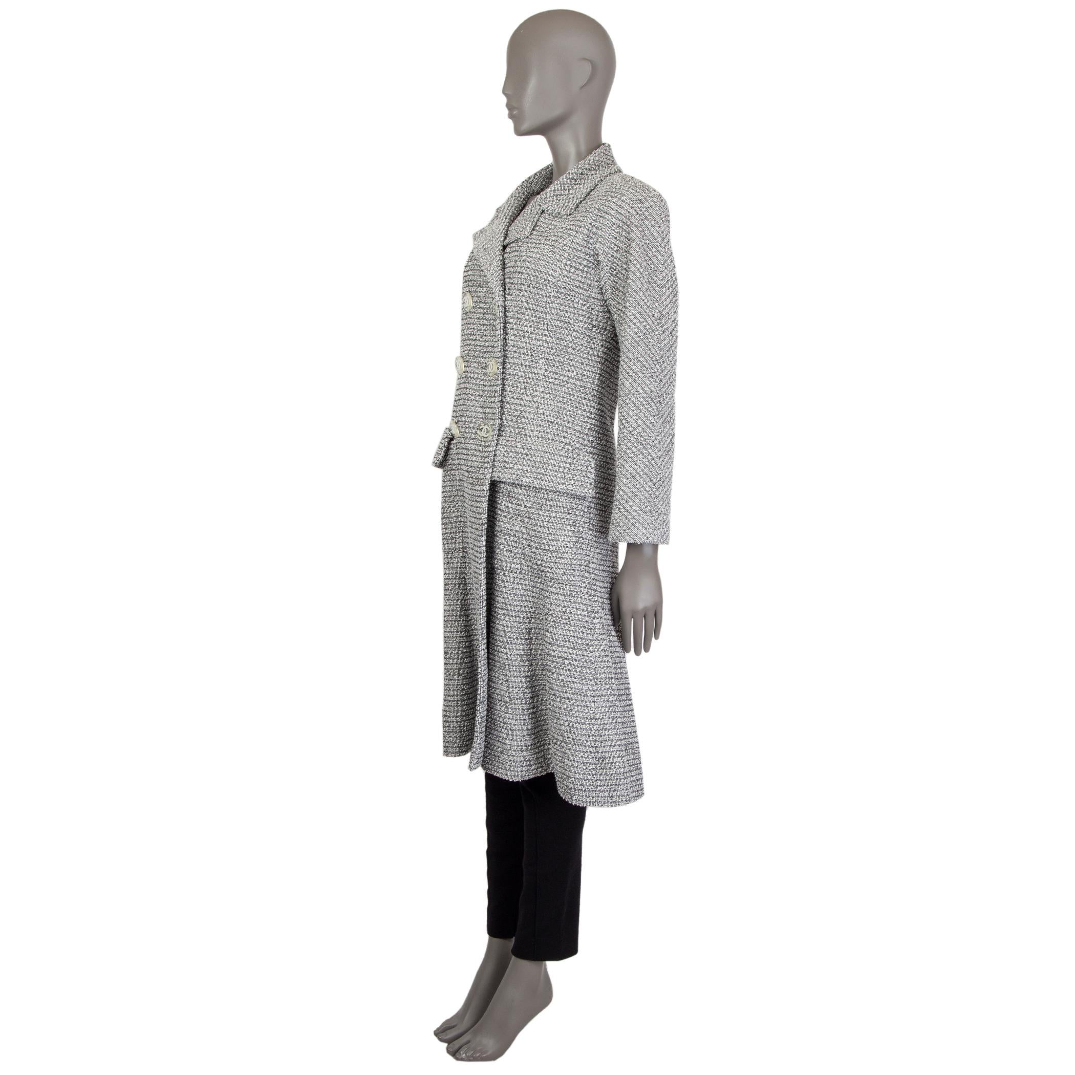 Chanel double-breasted tweed coat in black and white cotton (90%) and nylon (10%). With notch collar, two flap pockets on the sides, and peplum hemline. Closes with clear plastic and white CC buttons on the front. Lined in off-white camelia-print