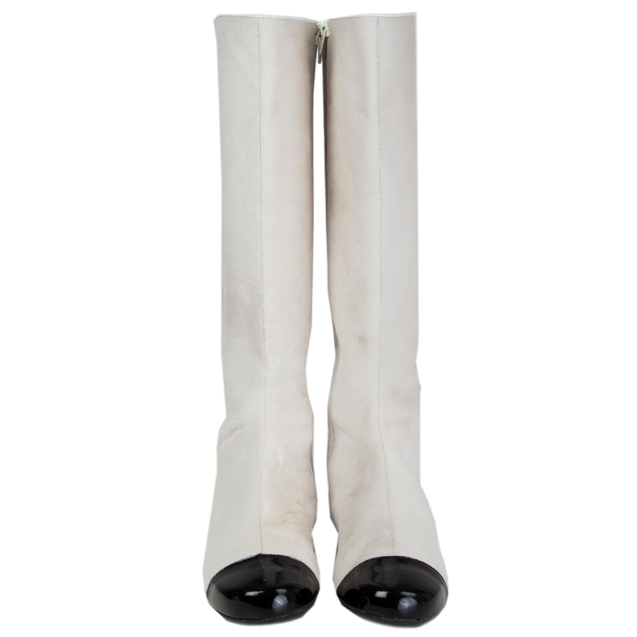 100% authentic Chanel flat knee-high boots in off-white calfhair with black patent leather tip and CC around the heel. Open with a zipper on the inside and are lined in white calfskin. Have been worn and are in excellent conditon. We couldn't find