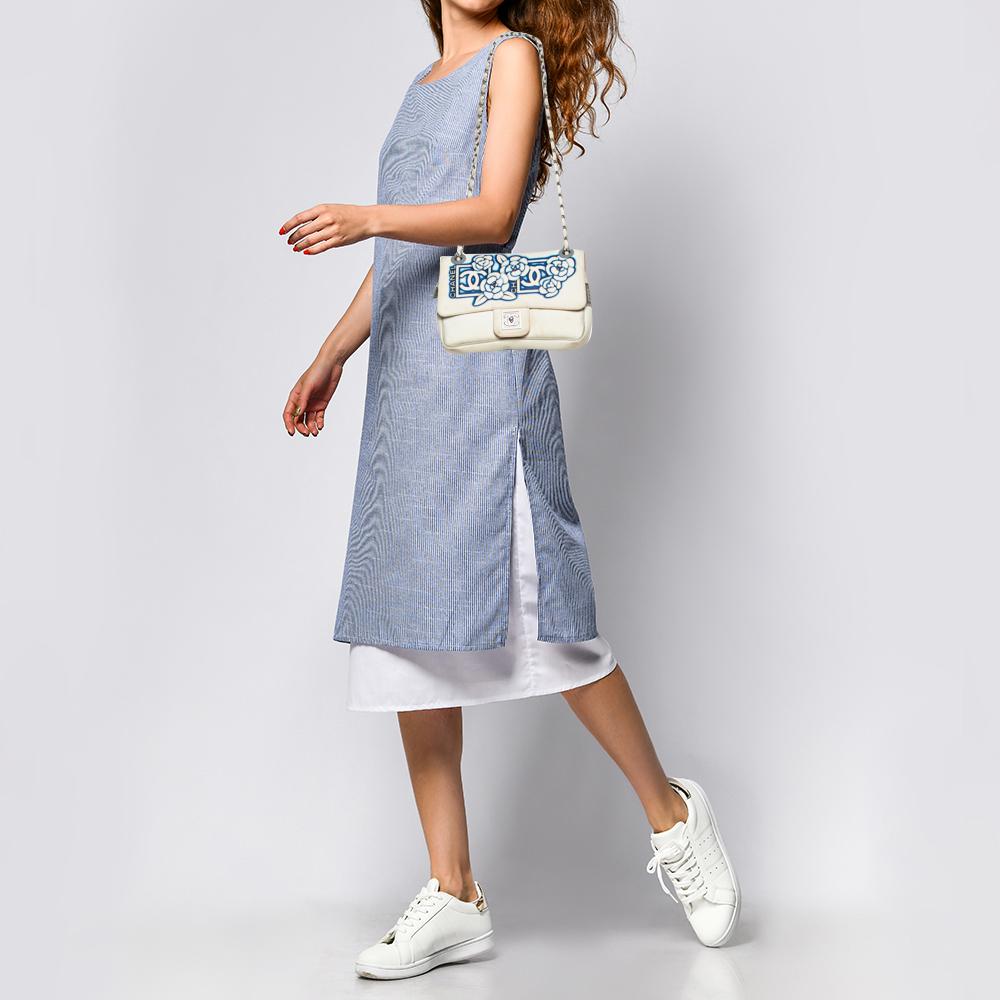 Schwingen Sie sich mit dieser Überschlagtasche von Chanel charmant durch jede Versammlung. Die aus Nylon gefertigte Tasche hat ein weißes Äußeres mit einer Klappe:: die mit den charakteristischen Aufdrucken und dem charakteristischen CC-Verschluss